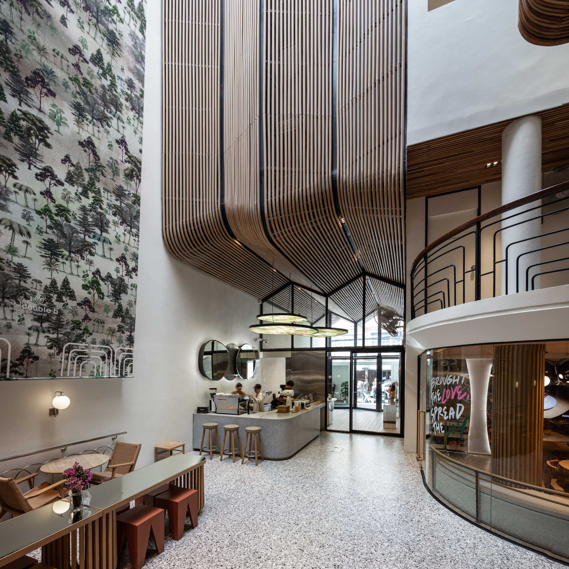 At the heart of the hostel, a light-filled internal courtyard with curved wooden facades and planted balconies offers a serene oasis amid the city’s tight urban fabric.