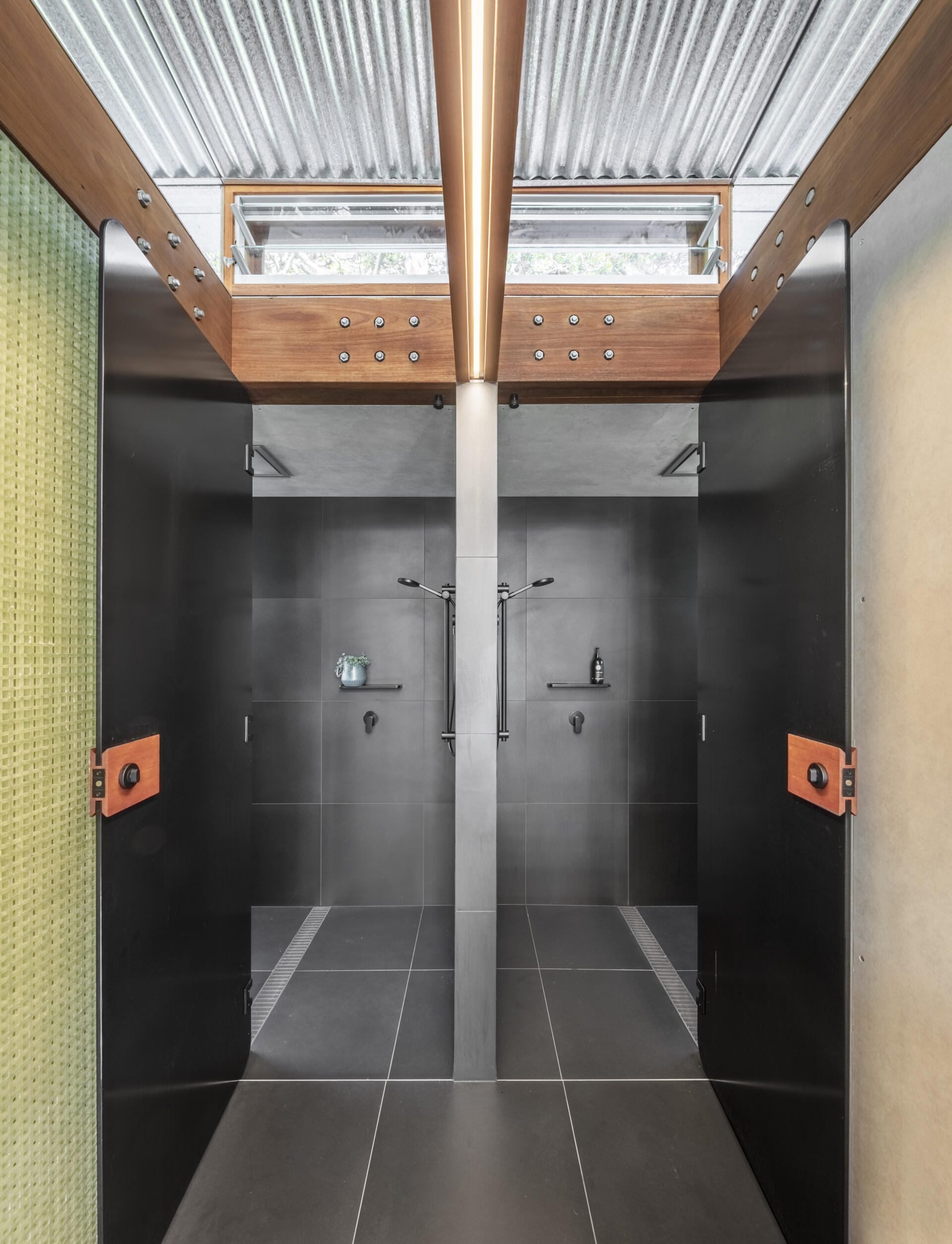 Dark charcoal tiles line the double shower, giving it a quiet, cocooned feel, while the finishes complement the vanity area.