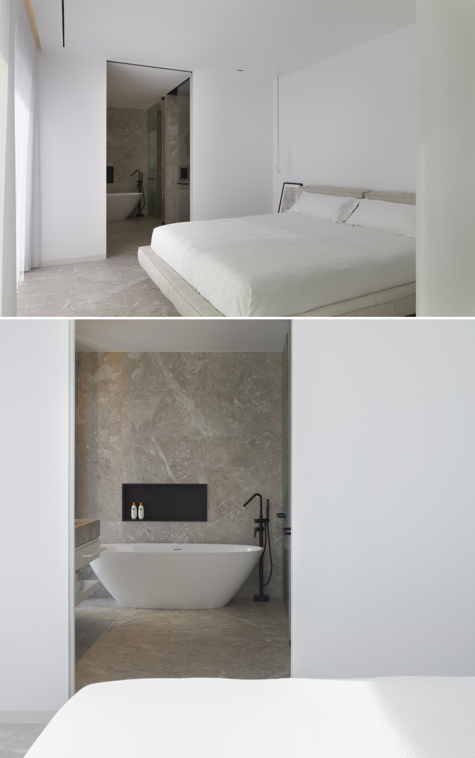 In the primary ensuite, a long stone vanity anchors this calming space, paired with softly glowing mirrors and matte black fixtures for contrast. Open shelves hold neatly folded towels, while a freestanding tub and black-lined recessed niche invite quiet, unhurried routines. Wrapped in soft gray stone, the shower pairs subtle texture with sharp black fixtures and a backlit niche. A frameless oval mirror adds a gentle curve, balancing the minimal palette with a quiet sense of care.
