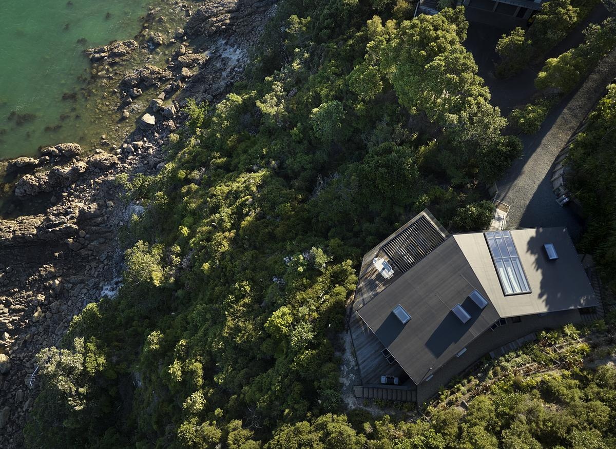 Perched high above the coastline, this striking modern home blends seamlessly into the lush hillside. Cantilevered over the cliff on slender steel supports, it features wraparound glass balustrade decks, warm timber cladding, and floor-to-ceiling glazing that frames panoramic views of the sea and sky. A bold, nature-integrated design that feels like a luxury treehouse.