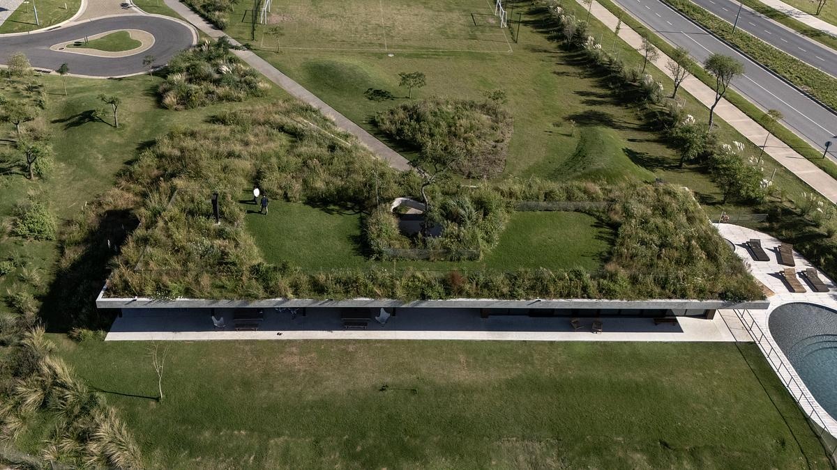 One of this project’s most striking features is its planted roof, which functions as both landscape and architecture. Instead of sitting on top of the building like an accessory, the green roof is woven into the terrain, folding down to meet the ground in a walkable ramp. This design move dissolves the boundary between natural and built, and subtly encourages people to interact with the space in ways that feel intuitive and playful.