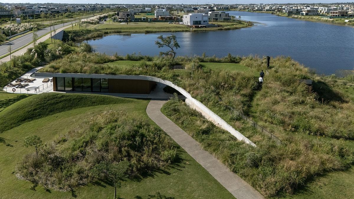 One of this project’s most striking features is its planted roof, which functions as both landscape and architecture. Instead of sitting on top of the building like an accessory, the green roof is woven into the terrain, folding down to meet the ground in a walkable ramp. This design move dissolves the boundary between natural and built, and subtly encourages people to interact with the space in ways that feel intuitive and playful.