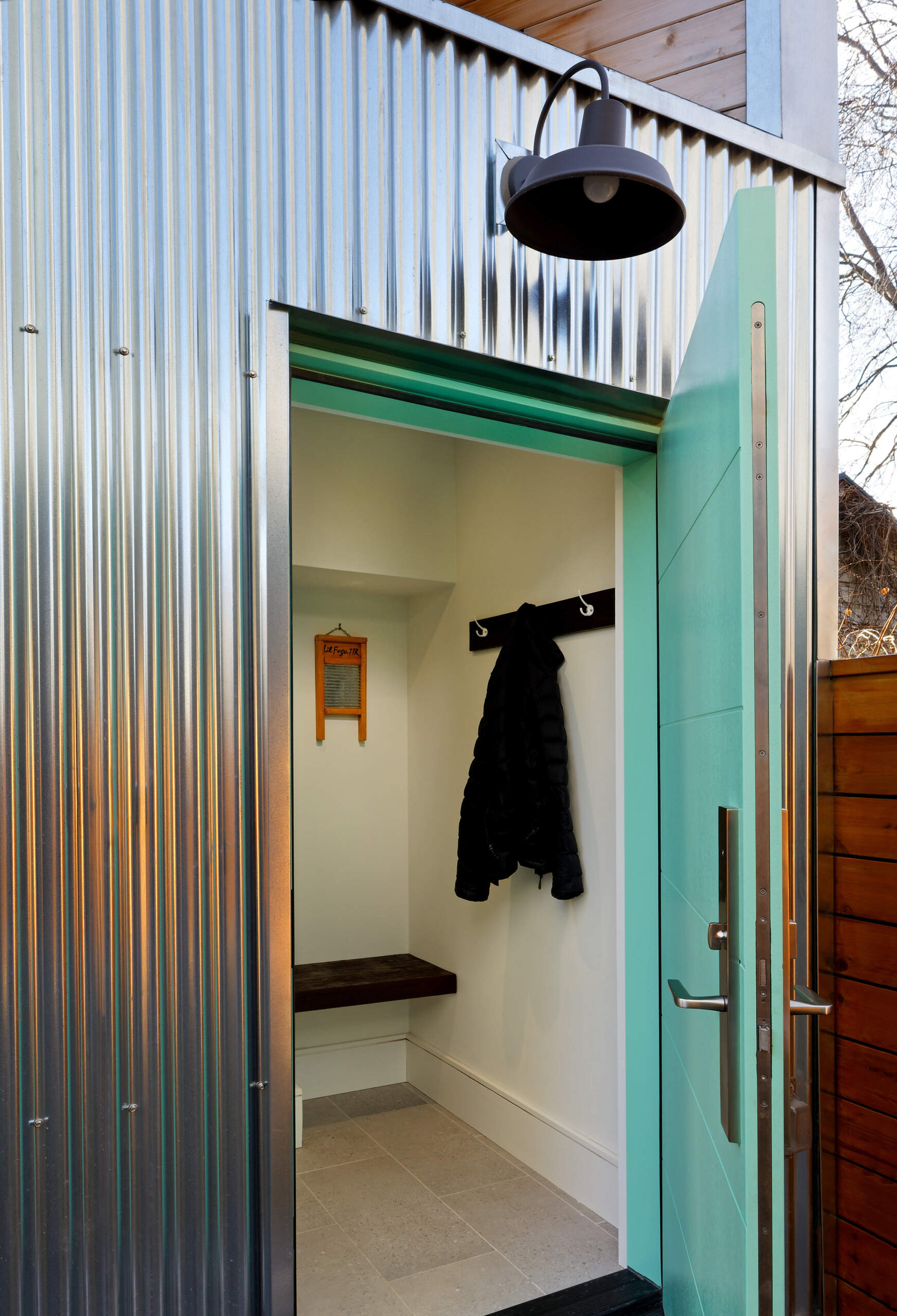 A pastel green front door hints at the thoughtful palette within this elevated laneway home. Step through, and a small entryway leads to a stairwell that rises into the main living area, a series of compact, carefully composed spaces.