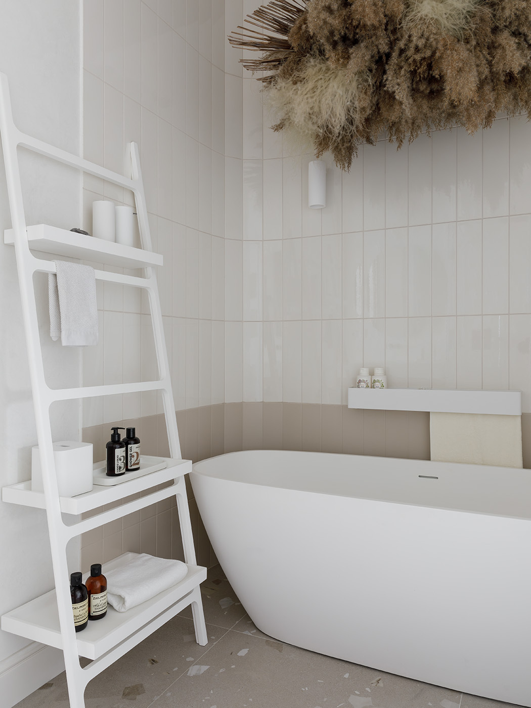 Above the freestanding Treesse bathtub, a custom dried flower installation evokes the banks of a river or lake, the natural environment of the symbolic stork.