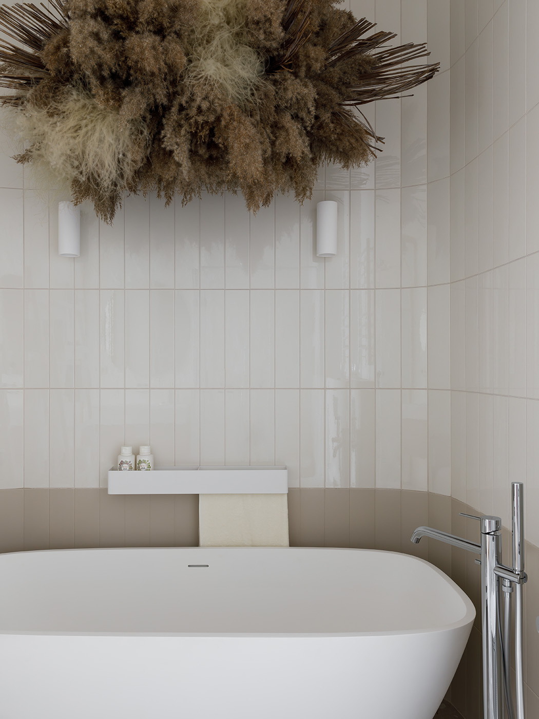 Above the freestanding Treesse bathtub, a custom dried flower installation evokes the banks of a river or lake, the natural environment of the symbolic stork.