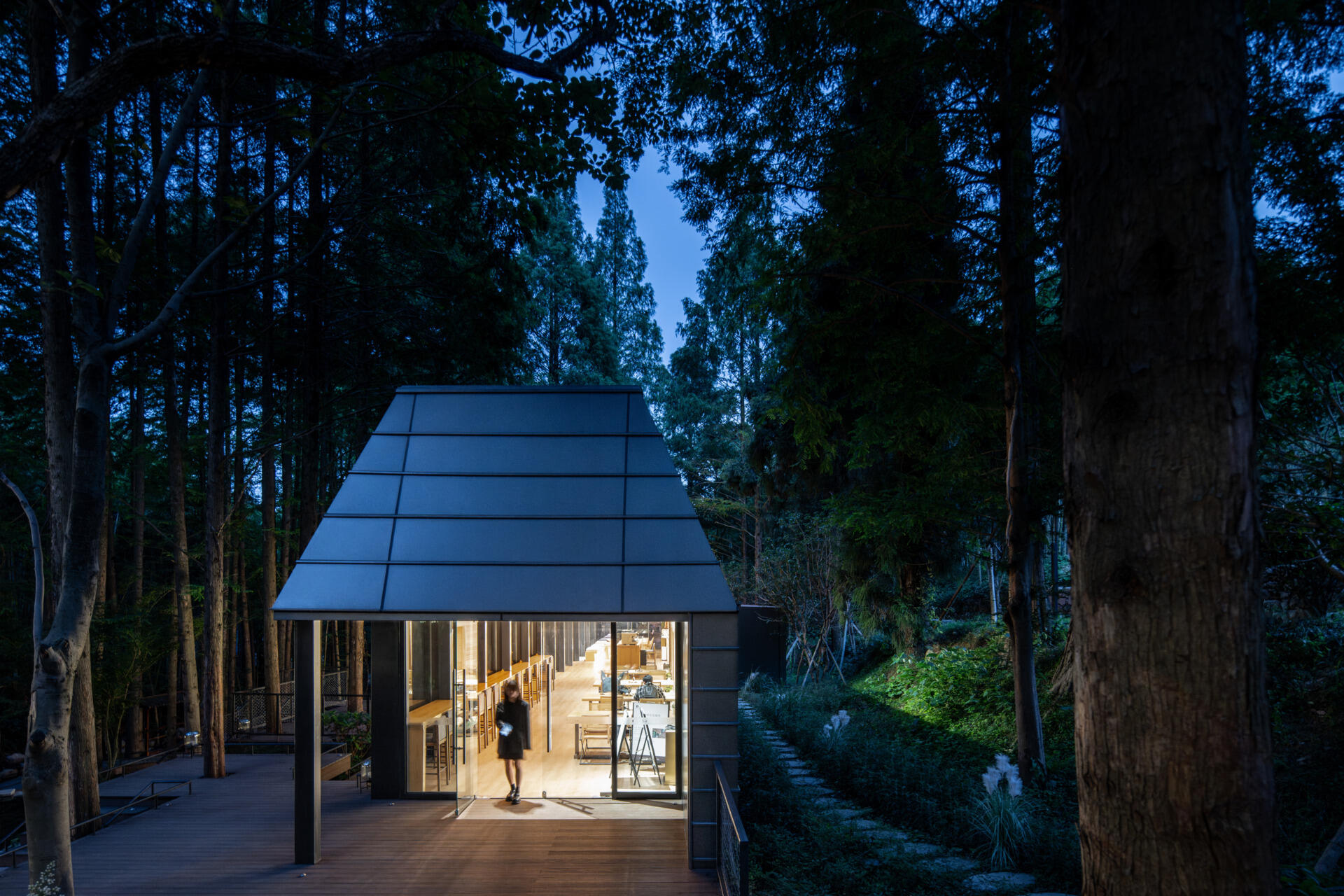 This modern reception space in a Hangzhou forest blurs the line between architecture and nature. Framed forest views and clerestory windows bring light and stillness into a structure shaped by the terrain.