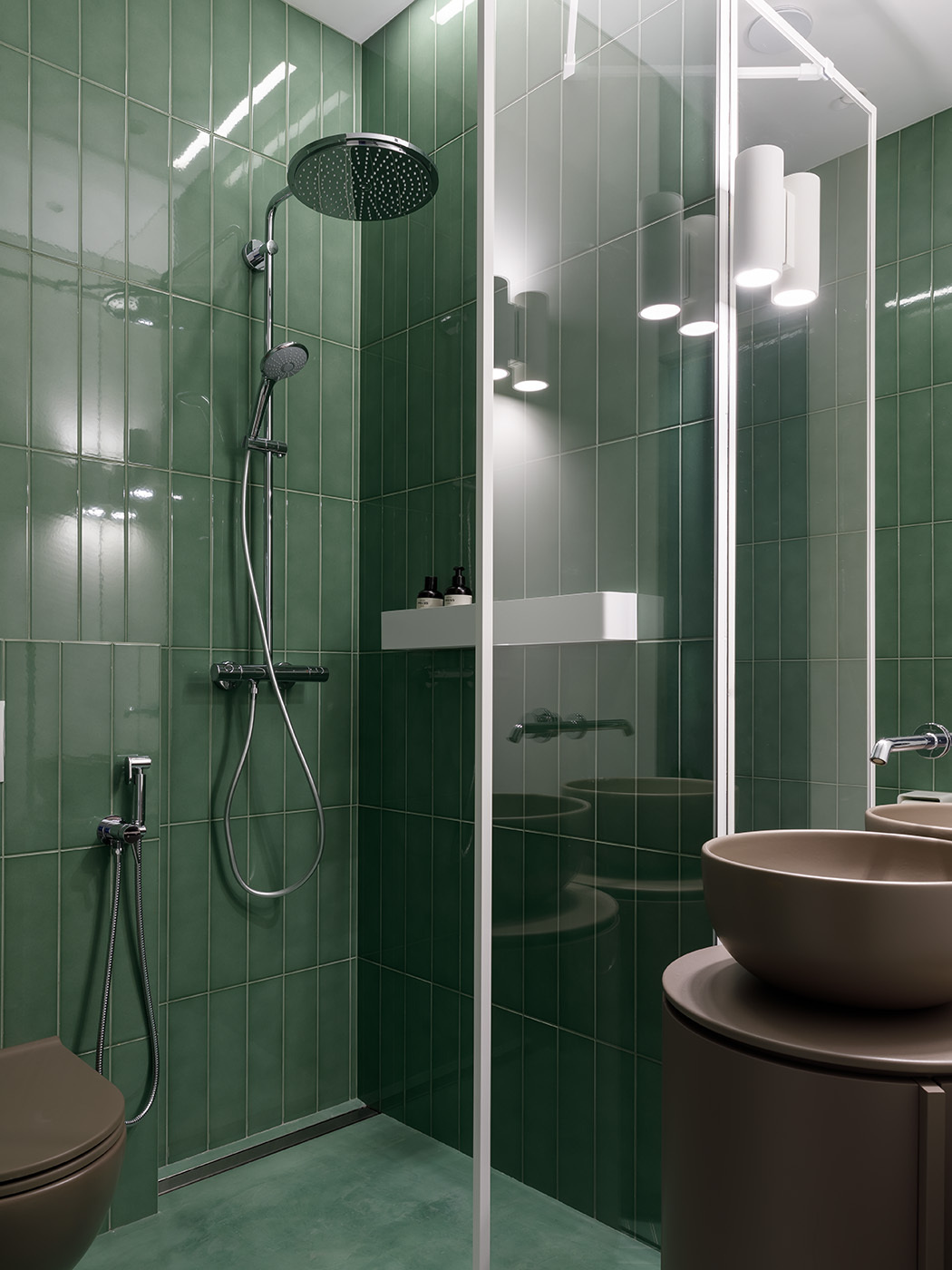 The guest bathroom features elegant vertical green tiles and a matching shower floor that add a calming splash of color, perfectly complementing the soft powder tones and clean-lined fixtures.