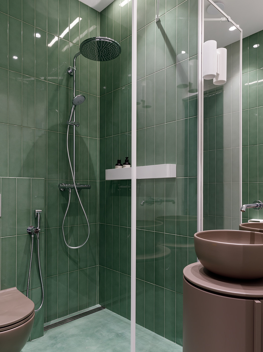 The guest bathroom features elegant vertical green tiles and a matching shower floor that add a calming splash of color, perfectly complementing the soft powder tones and clean-lined fixtures.
