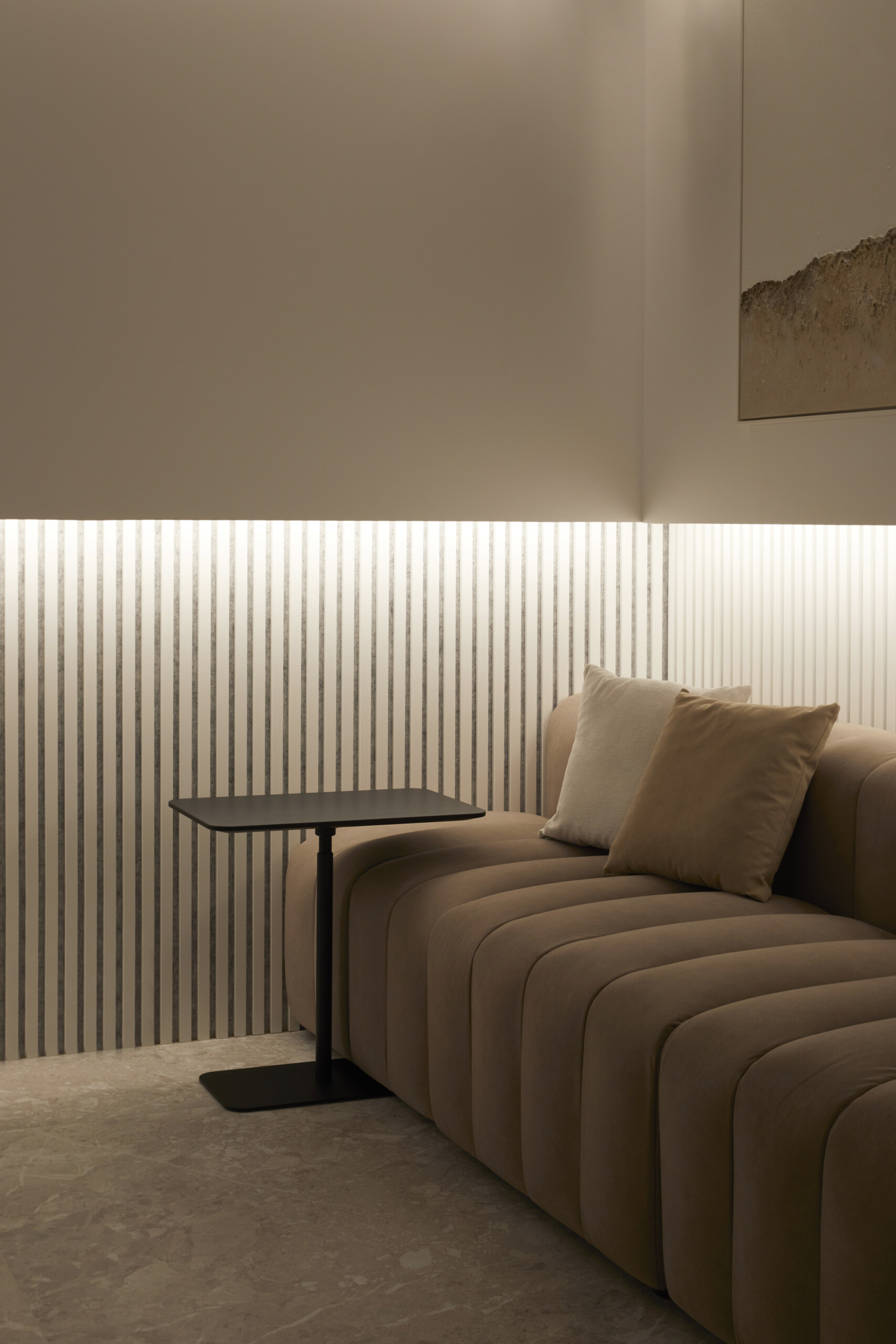 A multipurpose room made for ease, with home bar with hidden highlight, a tufted sofa, foosball table, and soft artwork lending the space a laid-back, lounge-like rhythm. Ribbed details and stone tiles carry the material palette through with texture and warmth.