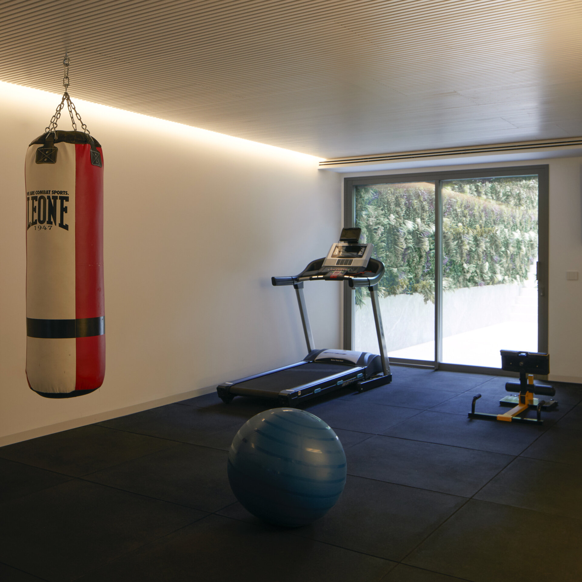 A modern home gym is part of a wellness zone that also includes a serene sauna and a flexible massage room, rounding out a space designed entirely for physical and mental recharge.