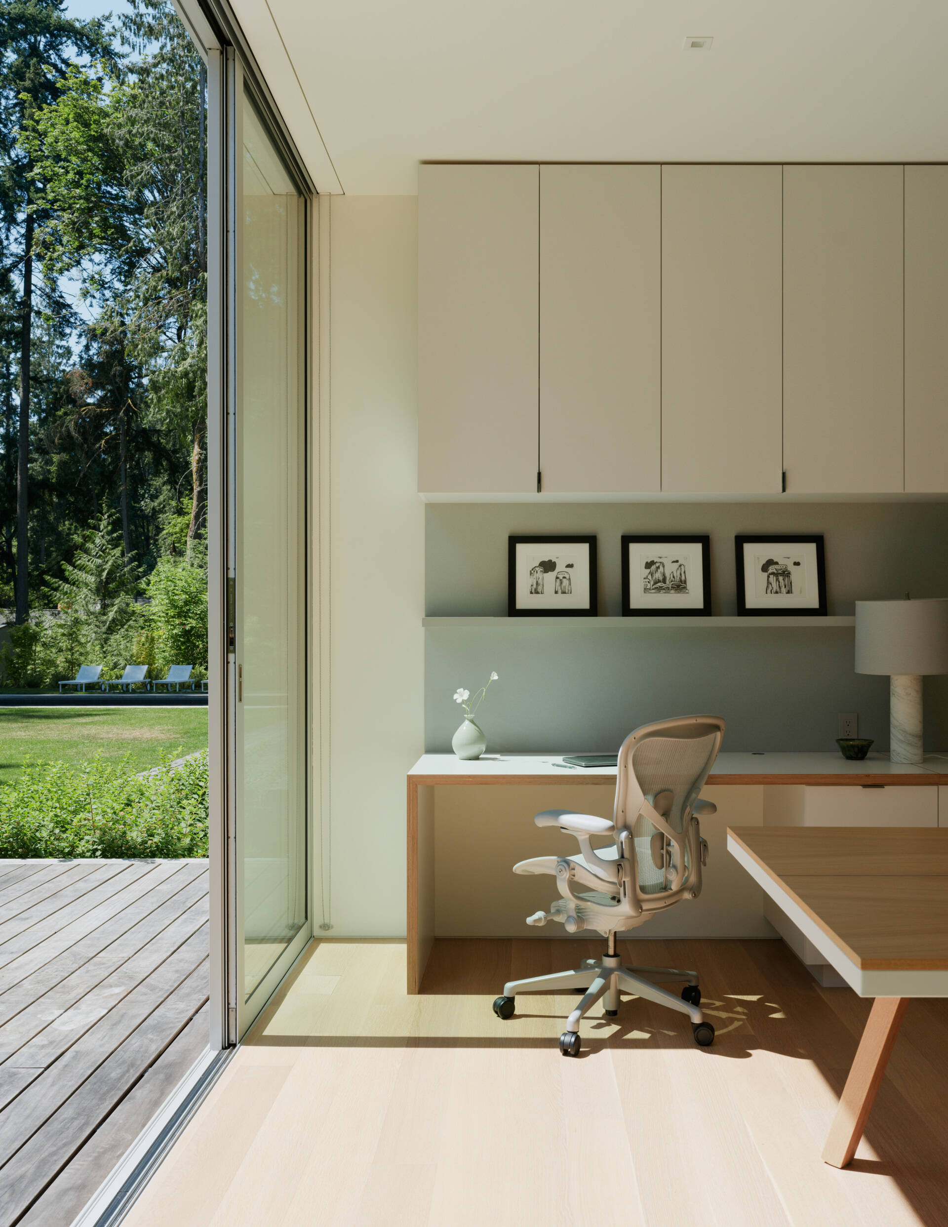 The home office benefits from the same attention to light and material found throughout the rest of the home. Floor-to-ceiling windows bring in views of the forest, creating a serene environment for work and focus. The furnishings are minimal but warm, designed to support productivity without visual clutter.