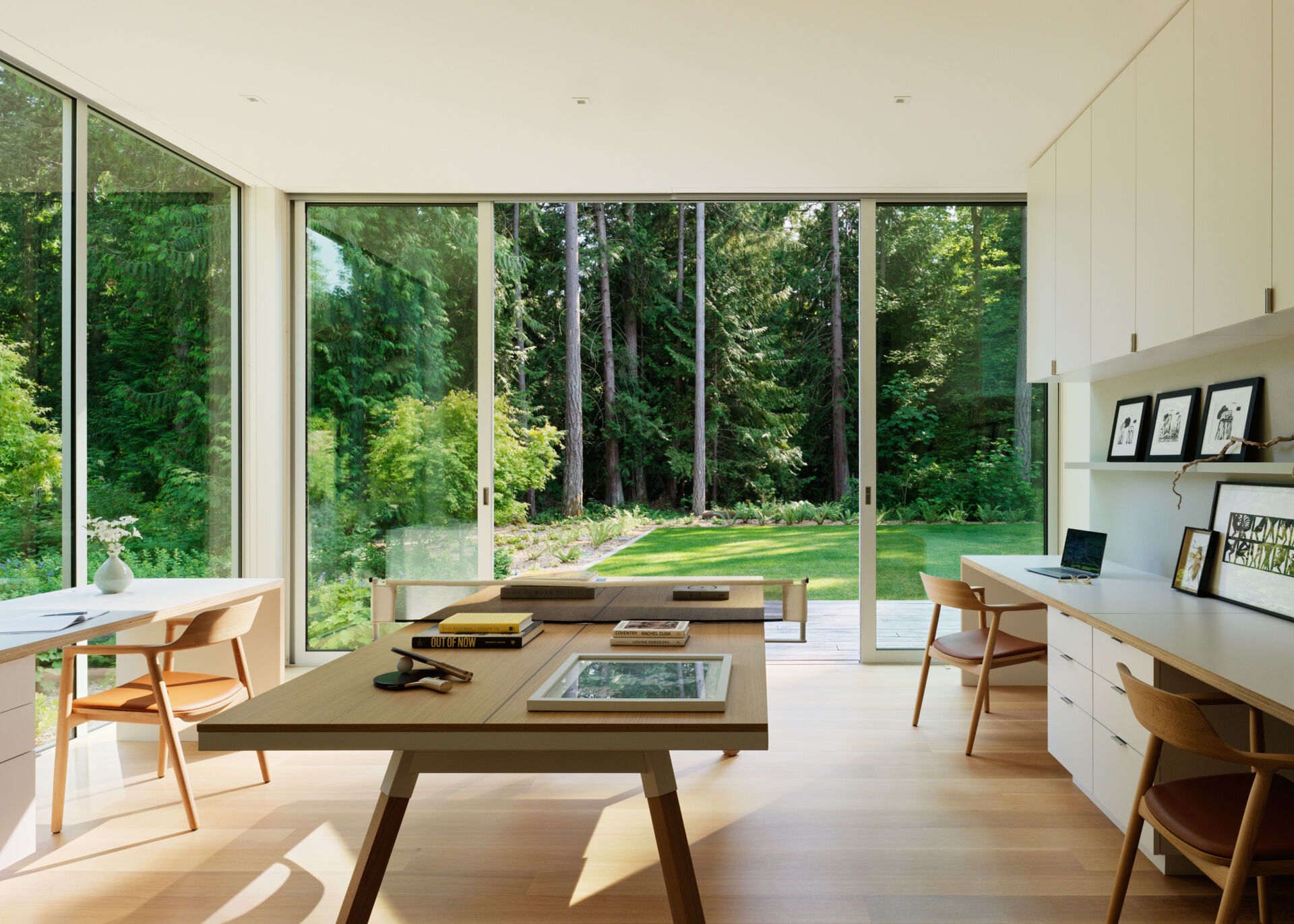 The home office benefits from the same attention to light and material found throughout the rest of the home. Floor-to-ceiling windows bring in views of the forest, creating a serene environment for work and focus. The furnishings are minimal but warm, designed to support productivity without visual clutter.
