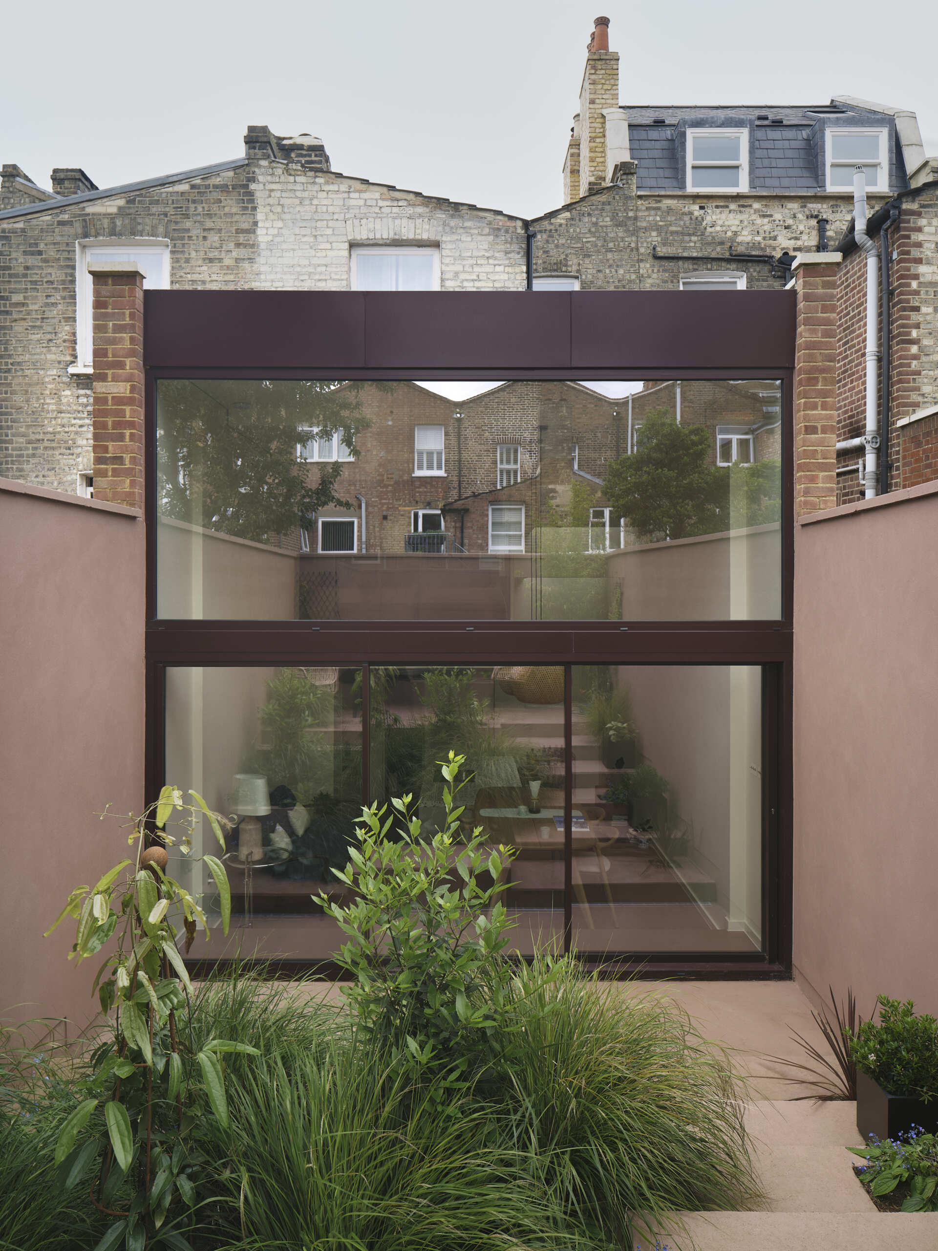 A key feature of this home’s transformation is the double-height volume at the rear, where tall windows flood the new space with natural light. These expansive panes extend sightlines from the kitchen through to the garden, making the lower ground floor feel open rather than enclosed.