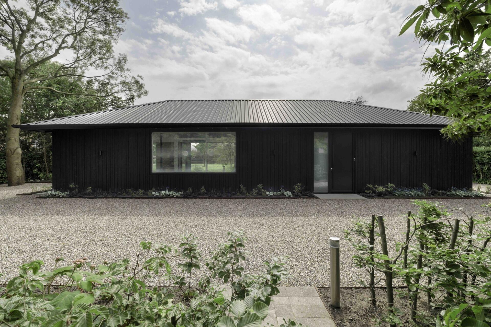 A modern and compact home with black waxed-wood cladding and extended rooflines.