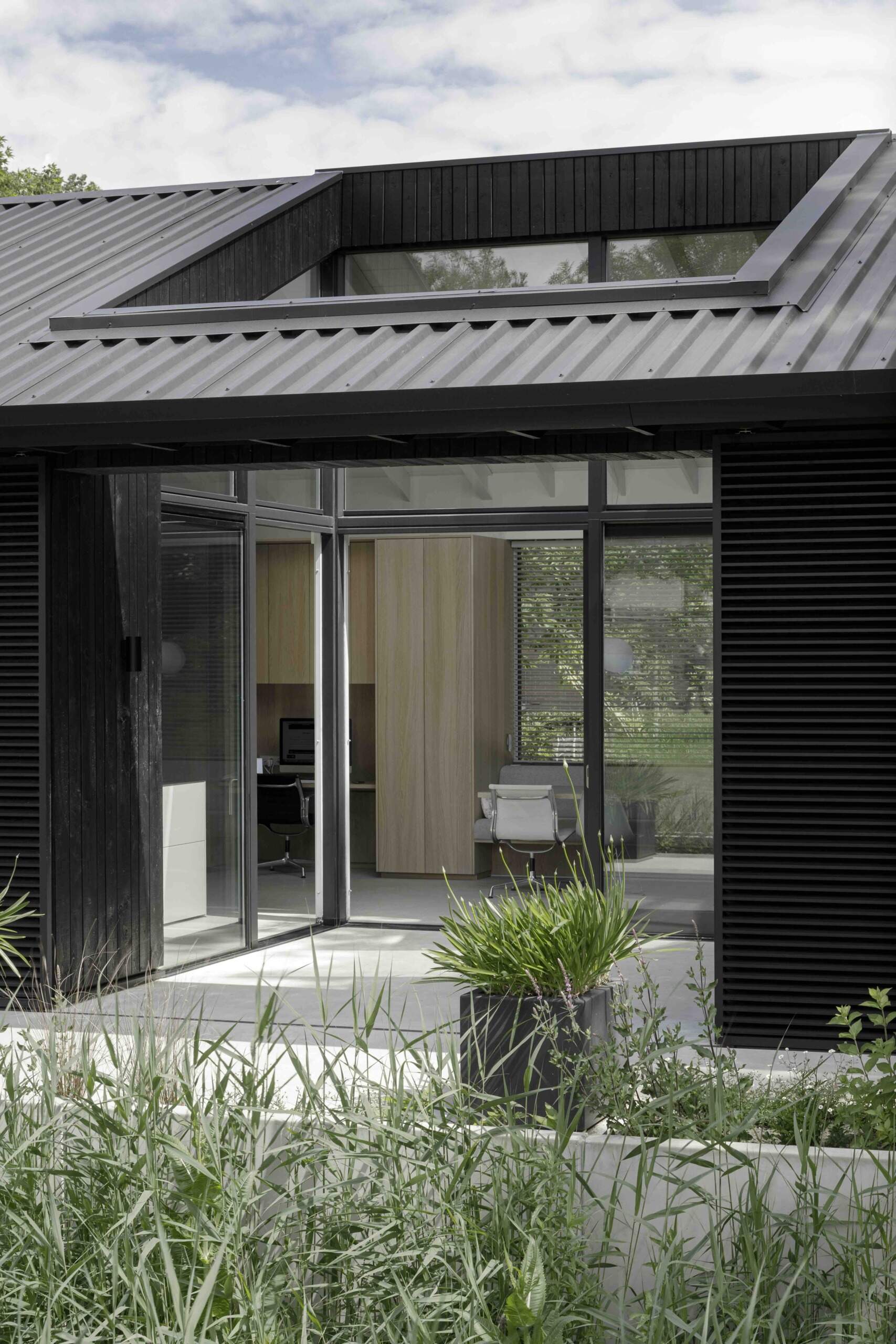 At the center of the home lies a private courtyard, framed by three retractable sliding doors. This patio expands the living area, becoming an outdoor room with seasonal flexibility. Whether filled with sun or shade, it anchors the house in nature and encourages year-round use.