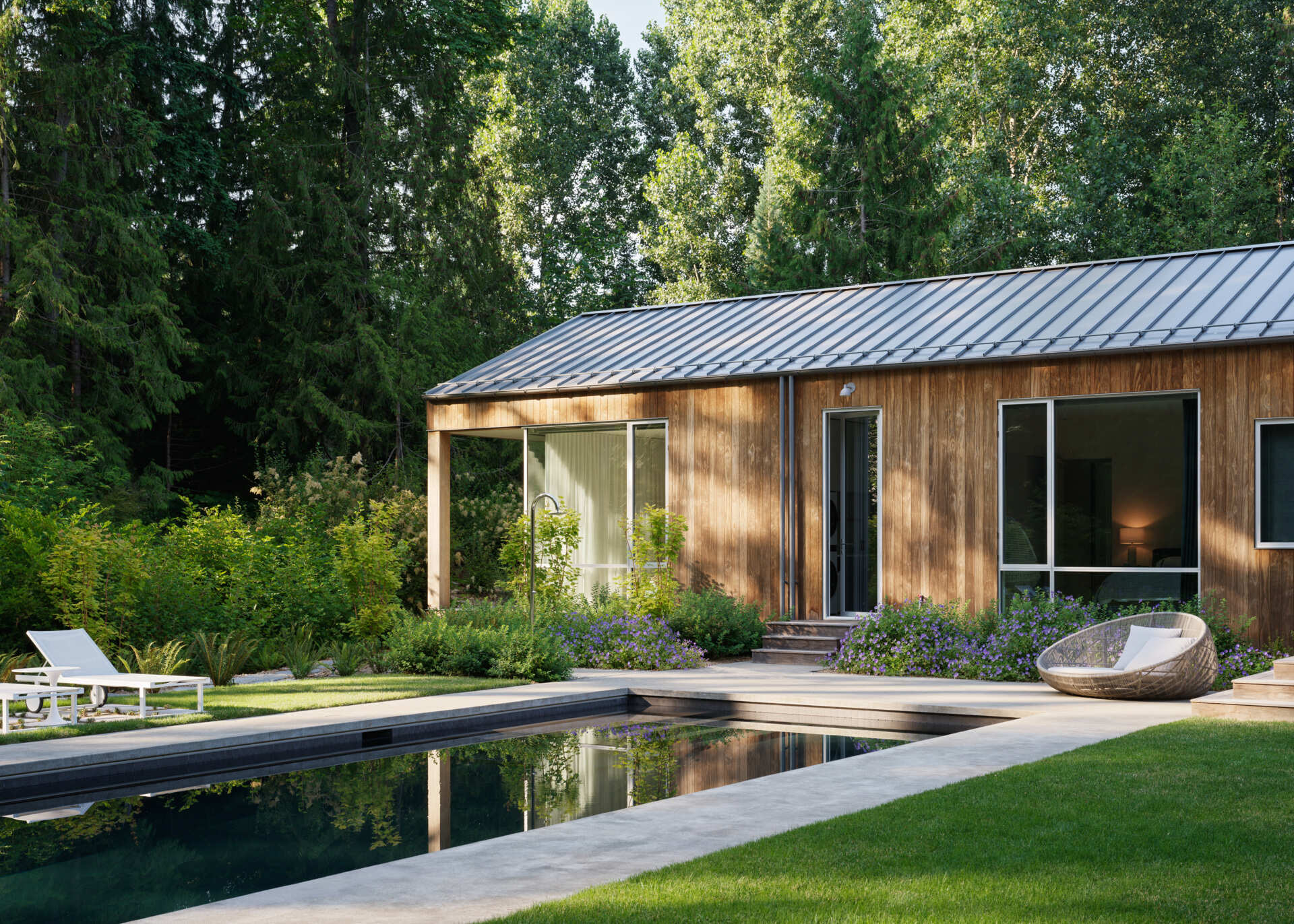 Outdoor life at this modern home is central to the family's daily rhythm. A generous lawn stretches out from the home, giving space for play and relaxation. At its far edge, a swimming pool and spa sit in full sun, paired with a stone-paved lounging terrace and outdoor shower.
