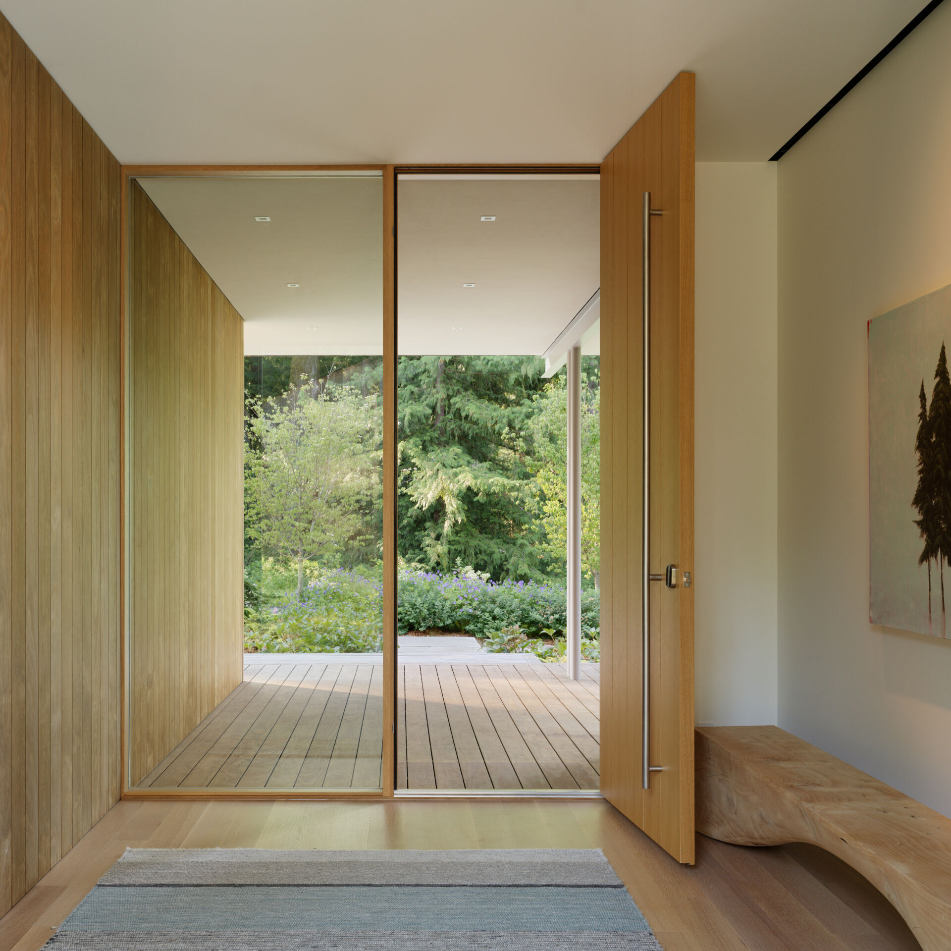 A wood front door provides a warm, tactile welcome. As it swings open, the transition from exterior to interior is seamless, the same materials and tones continue inside, reinforcing a sense of connection.