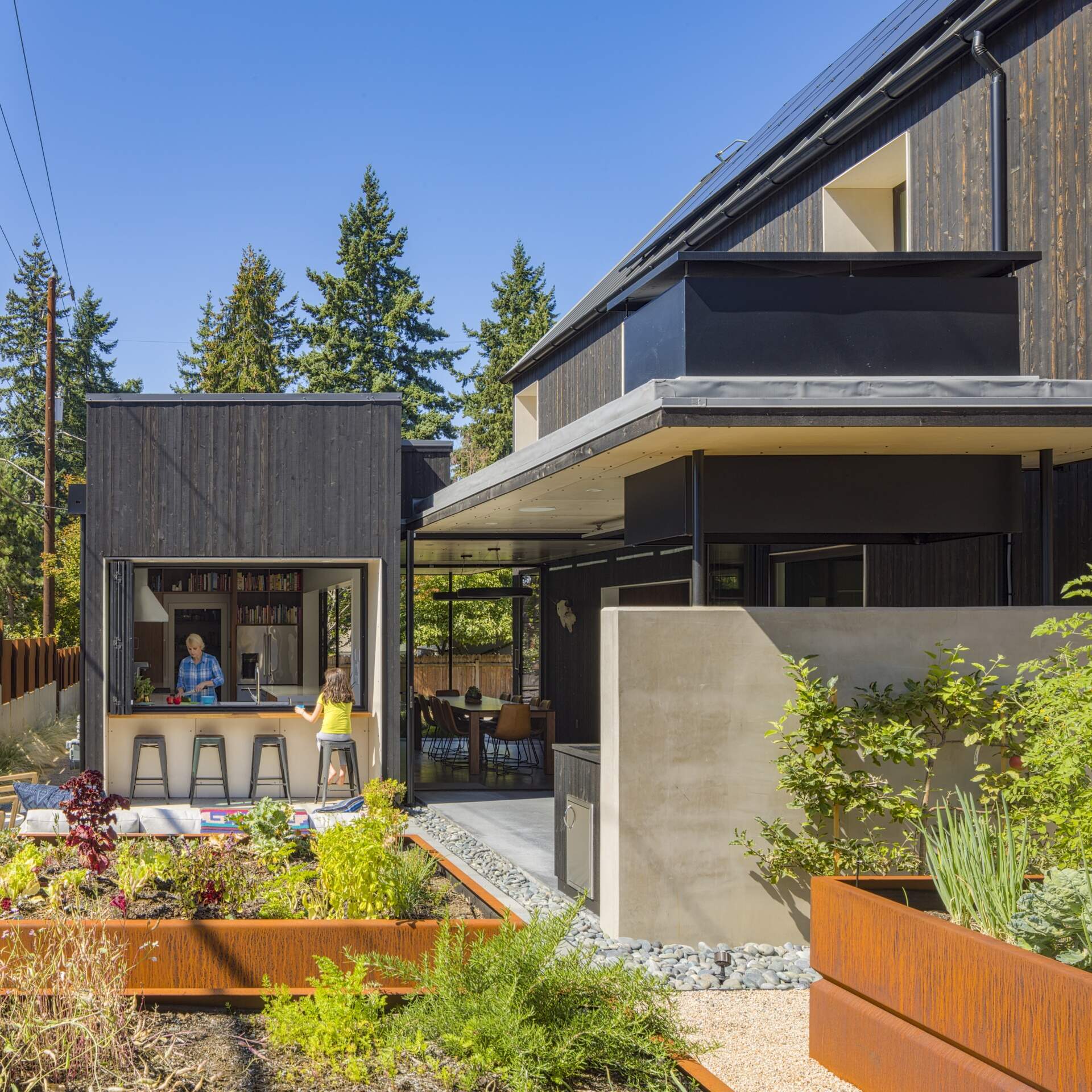 The kitchen opens directly to the courtyard through folding windows. This pass-through setup allows food and drinks to move easily between indoors and out, reinforcing the idea of the home as a continuous, adaptable space.