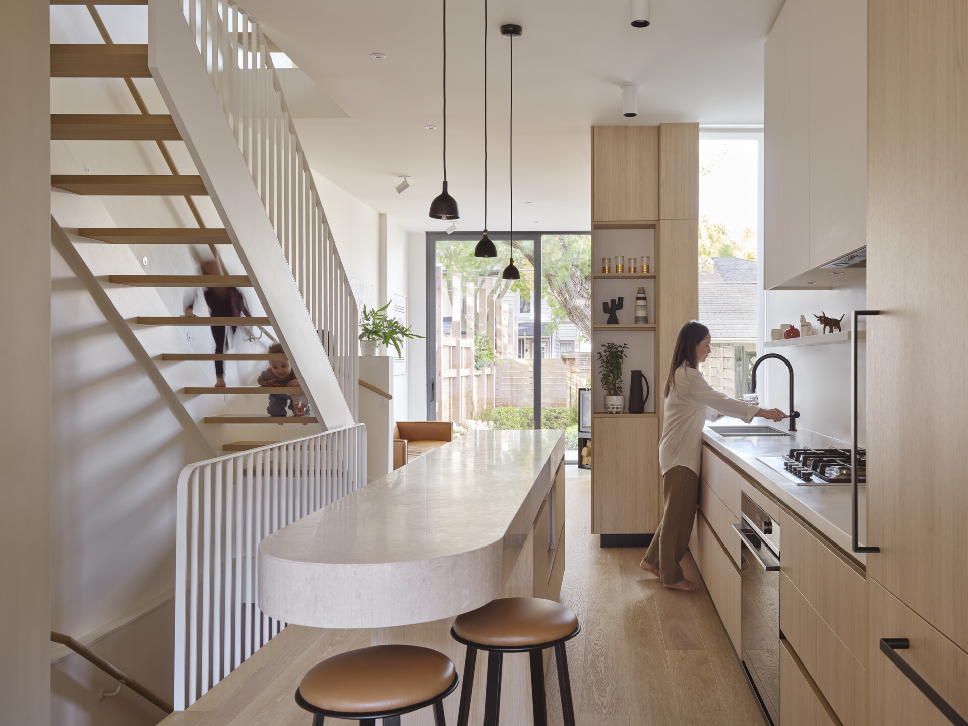 Get inspired by this light-filled kitchen with a cantilevered marble island, oak cabinetry, and clever storage solutions in a narrow urban footprint.