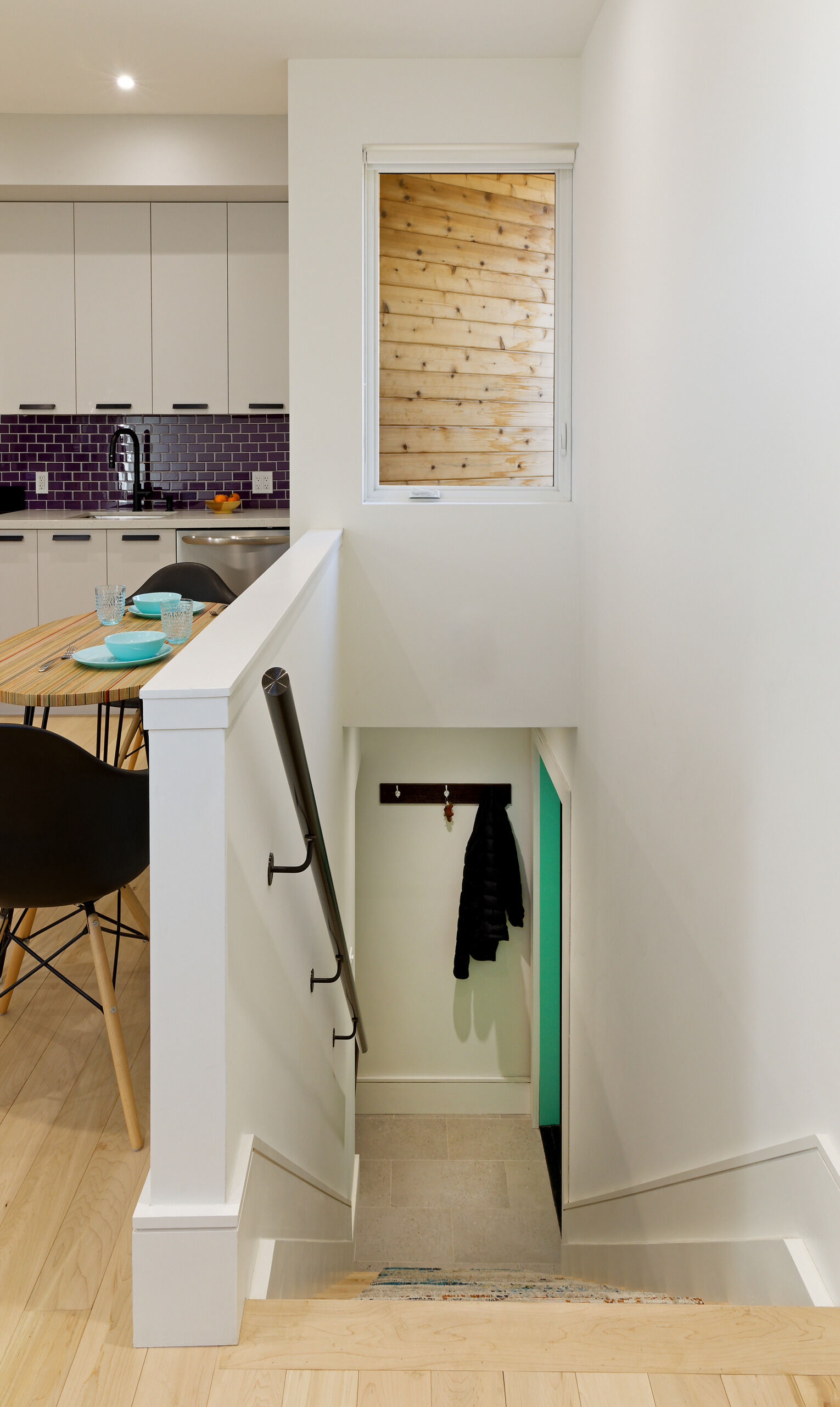 A pastel green front door hints at the thoughtful palette within this elevated laneway home. Step through, and a small entryway leads to a stairwell that rises into the main living area, a series of compact, carefully composed spaces.