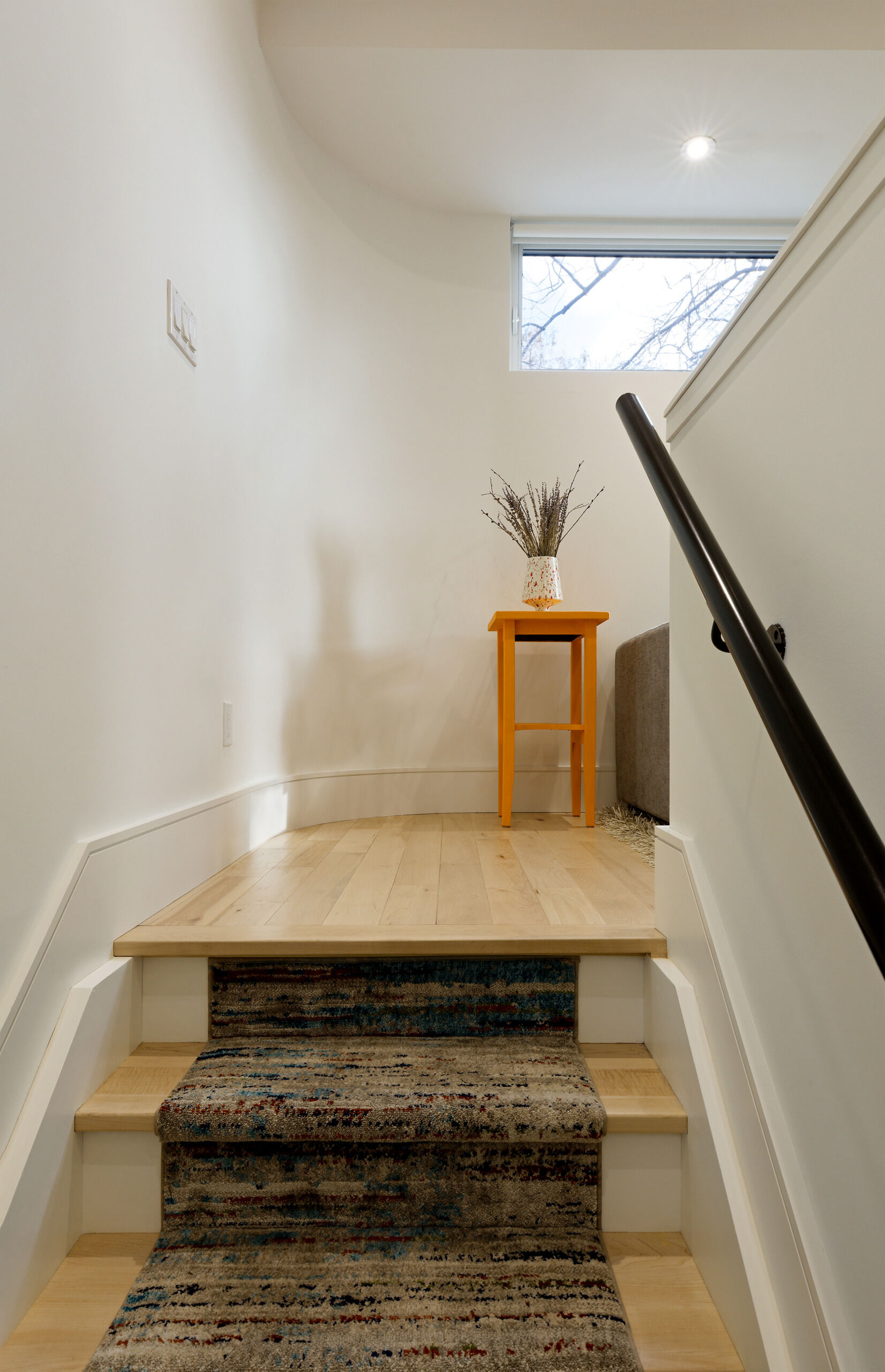 A pastel green front door hints at the thoughtful palette within this elevated laneway home. Step through, and a small entryway leads to a stairwell that rises into the main living area, a series of compact, carefully composed spaces.