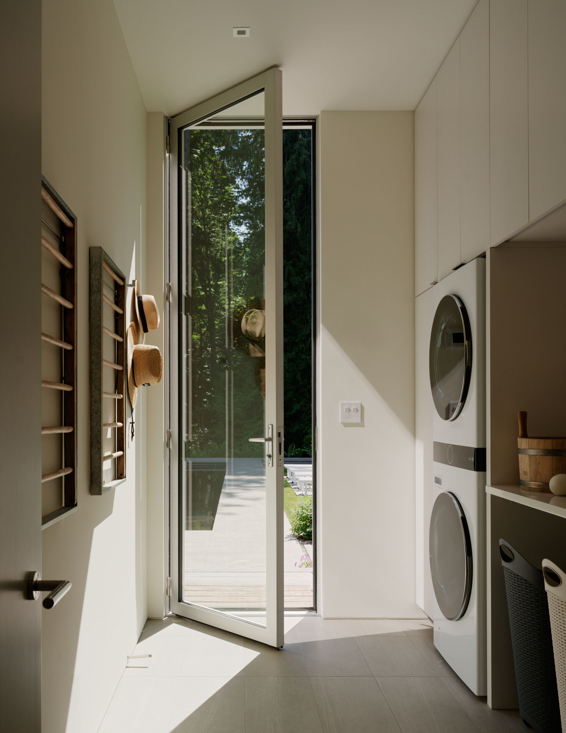 Tucked within the support wing of the house, the laundry room balances utility with design. Natural light filters in through the door, making the space feel open and pleasant rather than utilitarian. Simple cabinetry, durable countertops, and easy-to-clean finishes support the daily rhythms of family life. Like the rest of the home, the materials are chosen for longevity and ease, reinforcing a quiet elegance even in the most functional spaces.