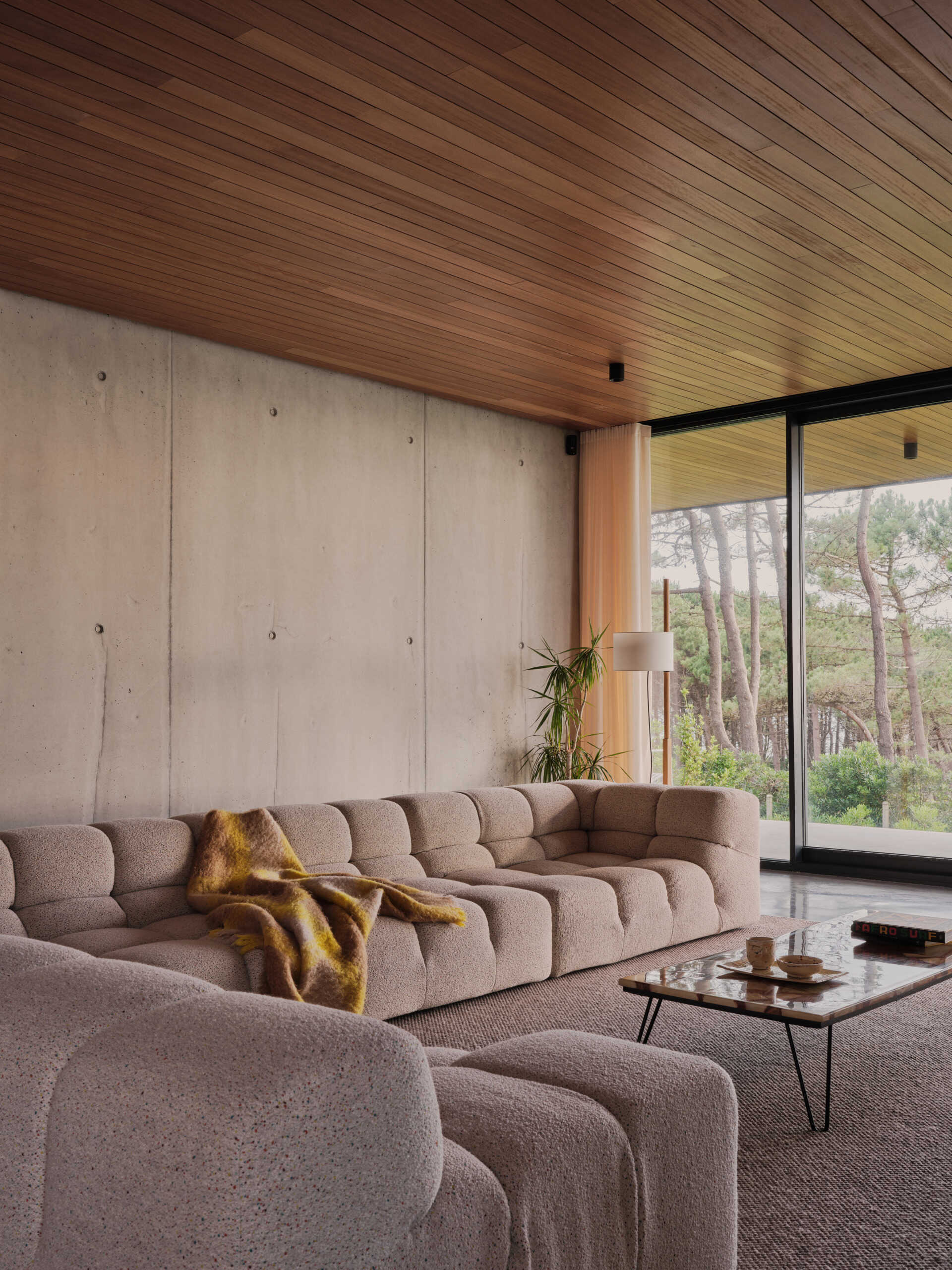 Slatted wood ceilings continue indoors, creating visual continuity with the landscape and echoing the home’s directional emphasis. The seamless integration of living, dining, and kitchen spaces reflects a contemporary approach to open-plan living, while materials and details root the experience firmly in place.