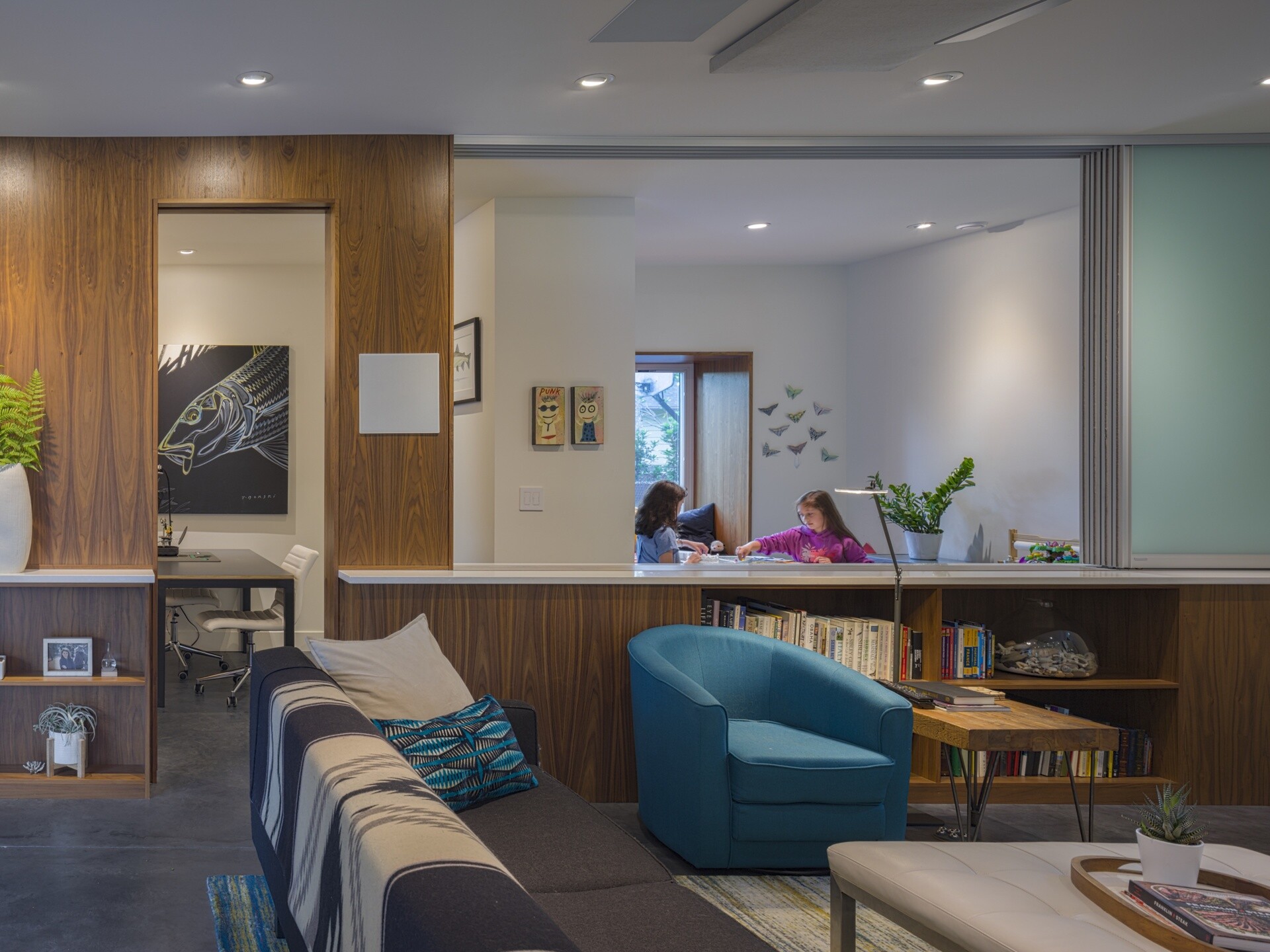 The family room doubles as a theater with built-in acoustic treatments and a sound system. Other rooms serve dual purposes: the guest room also functions as a workout area, and two craft rooms can be combined via a sliding partition. This flexible approach to program keeps the layout compact but responsive.