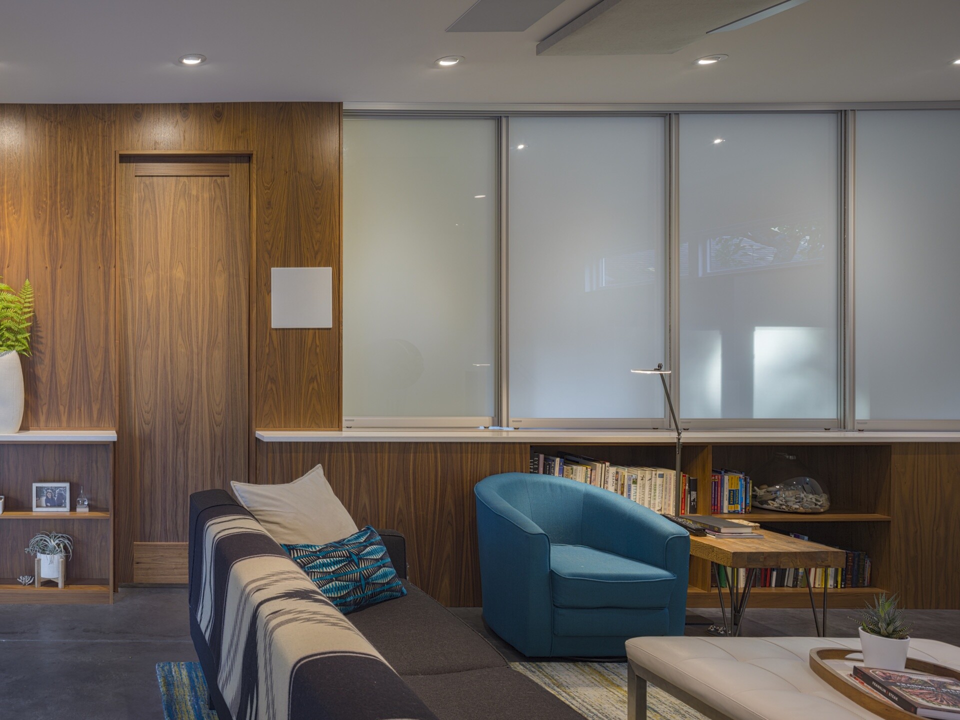 The family room doubles as a theater with built-in acoustic treatments and a sound system. Other rooms serve dual purposes: the guest room also functions as a workout area, and two craft rooms can be combined via a sliding partition. This flexible approach to program keeps the layout compact but responsive.