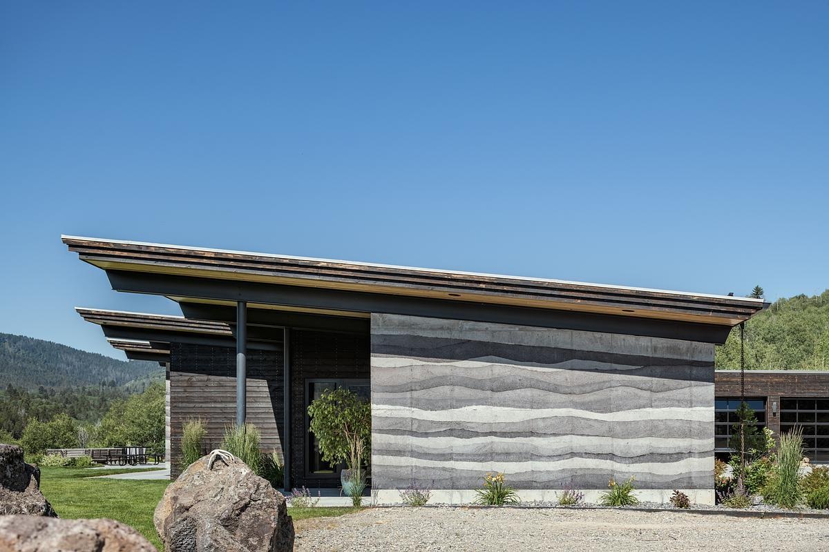 Rammed earth walls, clean lines, cantilevered roofs, and durable Shou Sugi Ban siding define the exterior of this modern mountain house built for extreme conditions.