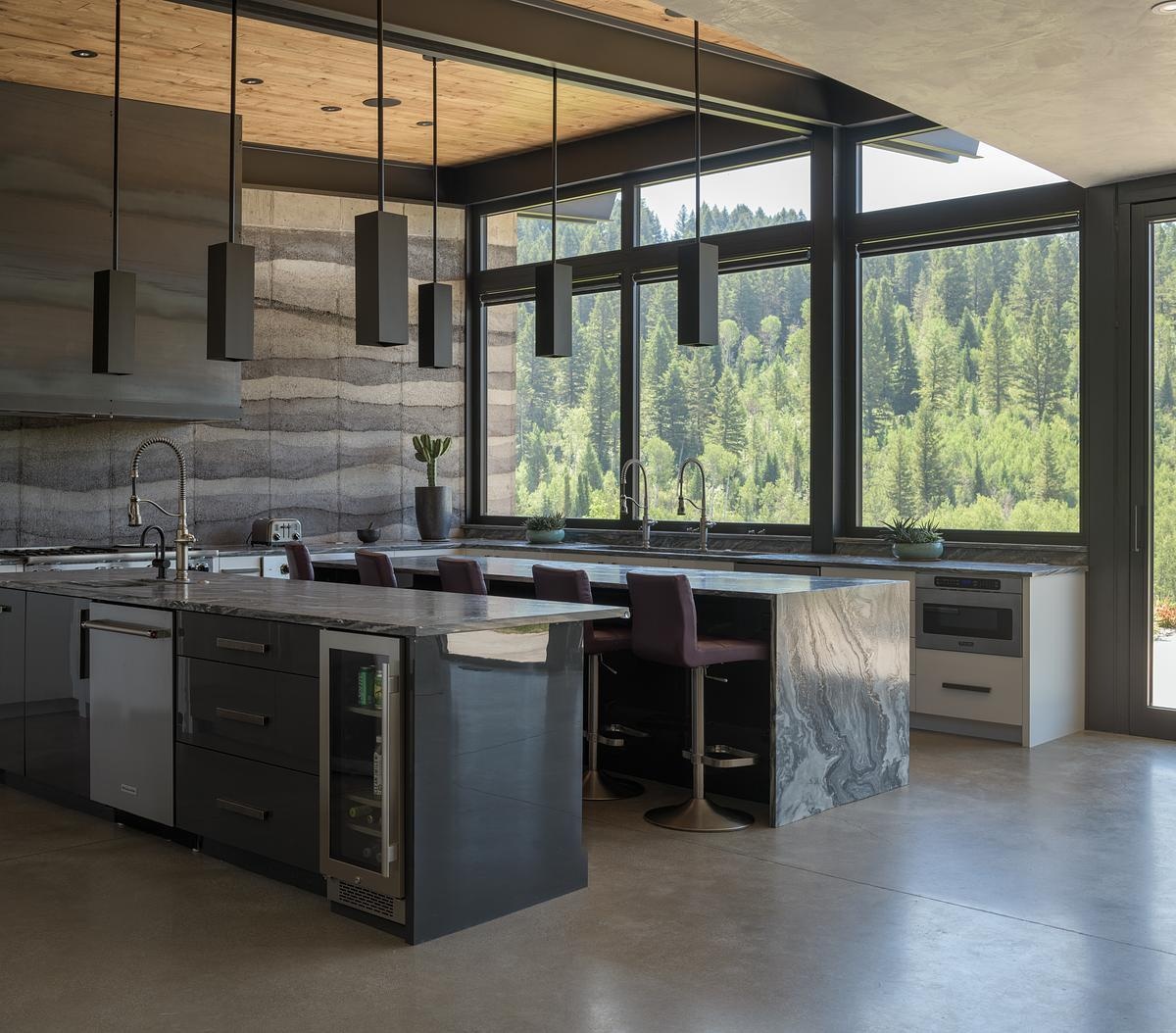 Inside, rammed earth walls, floor-to-ceiling windows, and polished concrete floors, create a unique interior look in this modern mountain house.