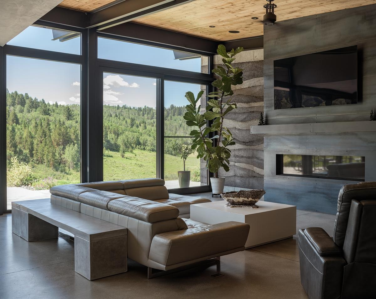 Inside, rammed earth walls, floor-to-ceiling windows, and polished concrete floors, create a unique interior look in this modern mountain house.