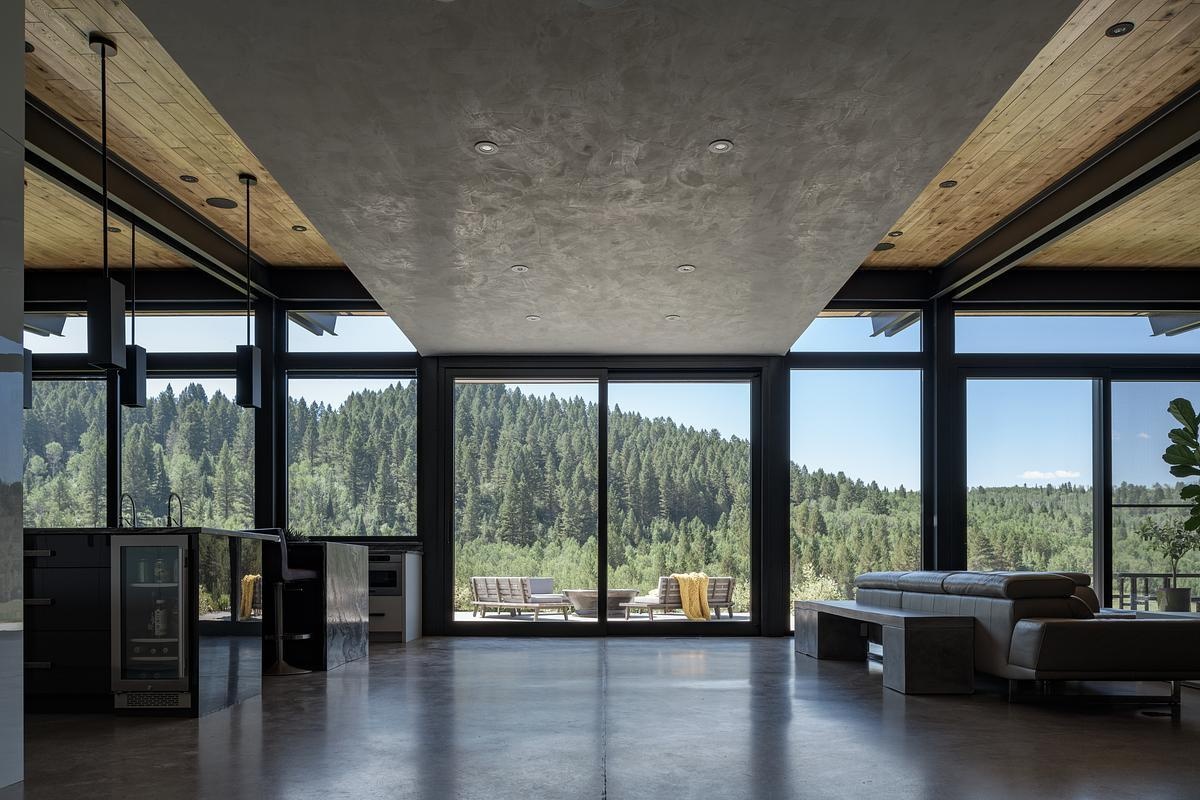 Inside, rammed earth walls, floor-to-ceiling windows, and polished concrete floors, create a unique interior look in this modern mountain house.