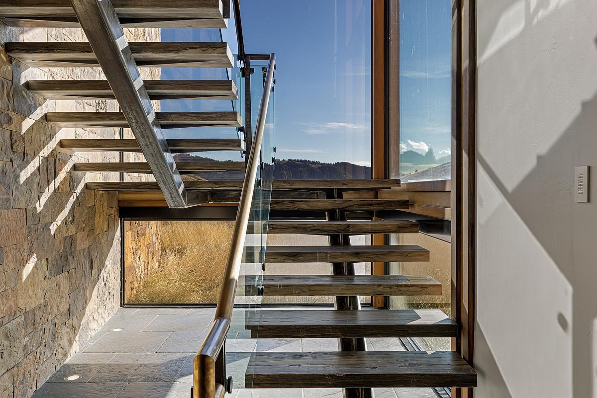 Throughout this home, like in the staircase, expansive windows are thoughtfully positioned to frame panoramic views of the surrounding mountain ranges.