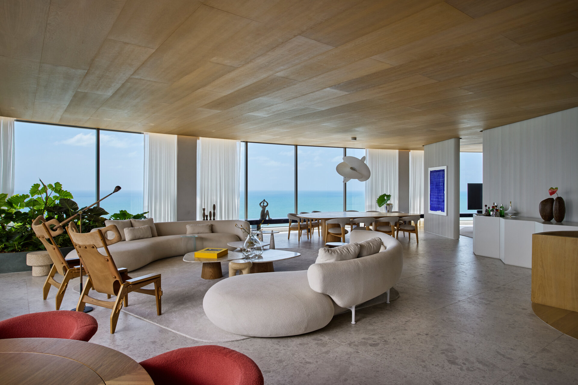 A full wall of windows frames panoramic ocean views in this Recife apartment. Neutral tones and curved furniture keep the focus on the horizon.