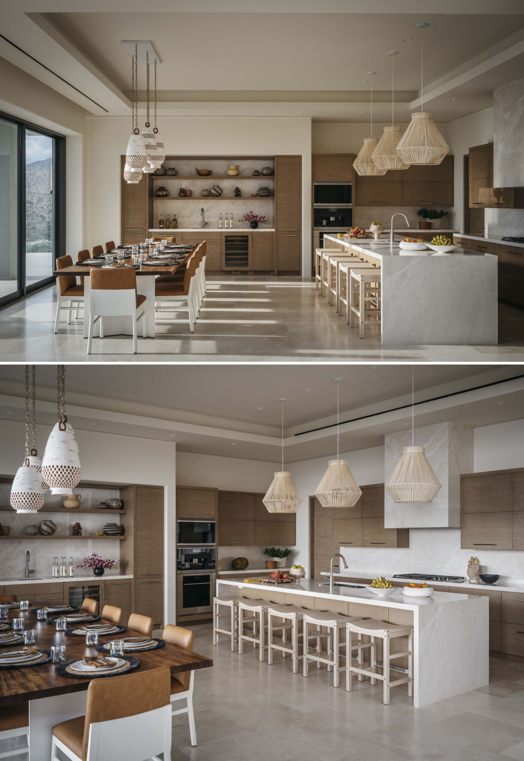 This kitchen and dining area strikes a beautiful balance between spacious and inviting, with soft tones and organic textures that make the whole space feel grounded and warm. The creamy stone floors and natural wood cabinetry create a soothing backdrop, while the large marble island serves as both a functional centerpiece and a sculptural statement. Overhead, woven pendant lights add a layer of texture and cast gentle shadows across the surfaces below. The dining table, rich with wood grain and surrounded by caramel-toned leather chairs, feels ready for everything from family meals to long, laughter-filled evenings with guests. Open shelving along the back wall displays artful ceramics and natural accents, adding personality without clutter. Floor-to-ceiling windows flood the room with sunlight and offer a view of the surrounding mountains, making the space feel connected to nature even when indoors.
