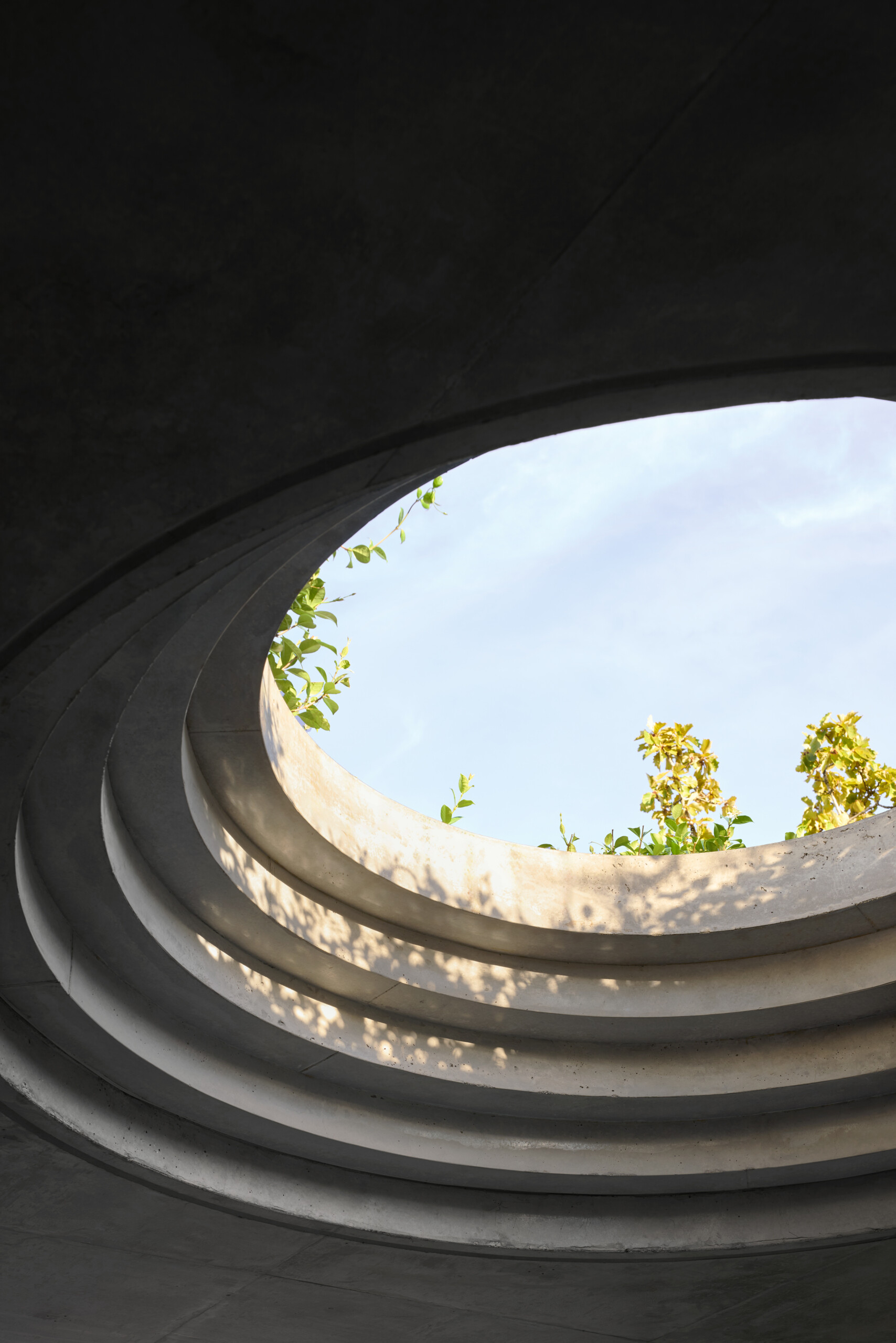 A defining feature of the rear of this remodeled home is a courtyard with a large circular cut-out overhead, a bold geometric move that invites sky views and dappled sunlight into the space below. Positioned above the outdoor dining area, the cut-out frames the moment, turning the patio into more than just a transitional space.