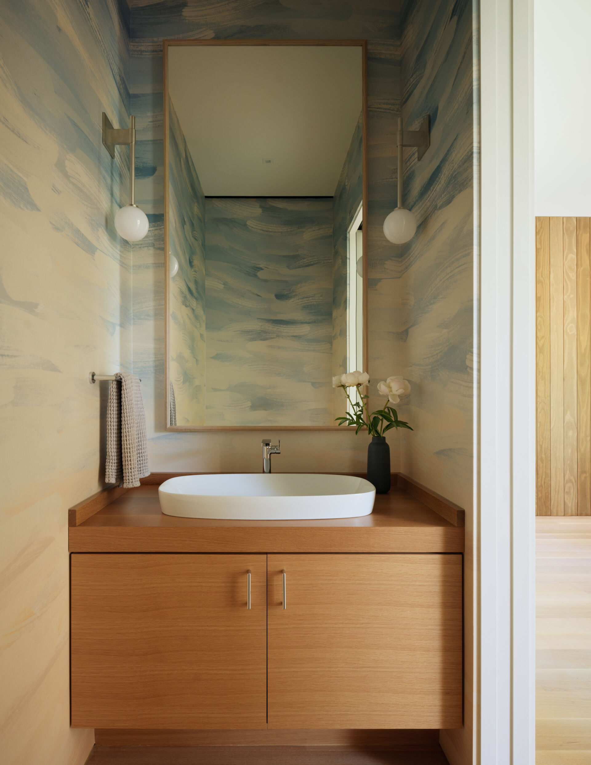 Though compact in size, the powder room is designed with the same care and intention found throughout the home. It offers a moment of contrast and personality, a space where wallpaper can take center stage.