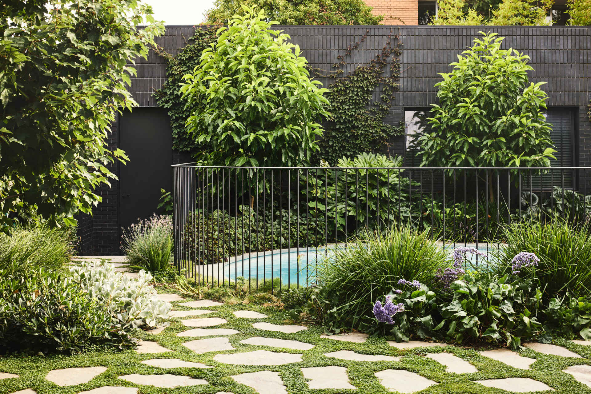 This modern landscaping plays a crucial role in defining the sanctuary-like atmosphere. With a round swimming pool, outdoor fireplace, strategic planting, and thoughtful layering, the outdoor spaces offer both privacy from the street and a lush backdrop for daily life.