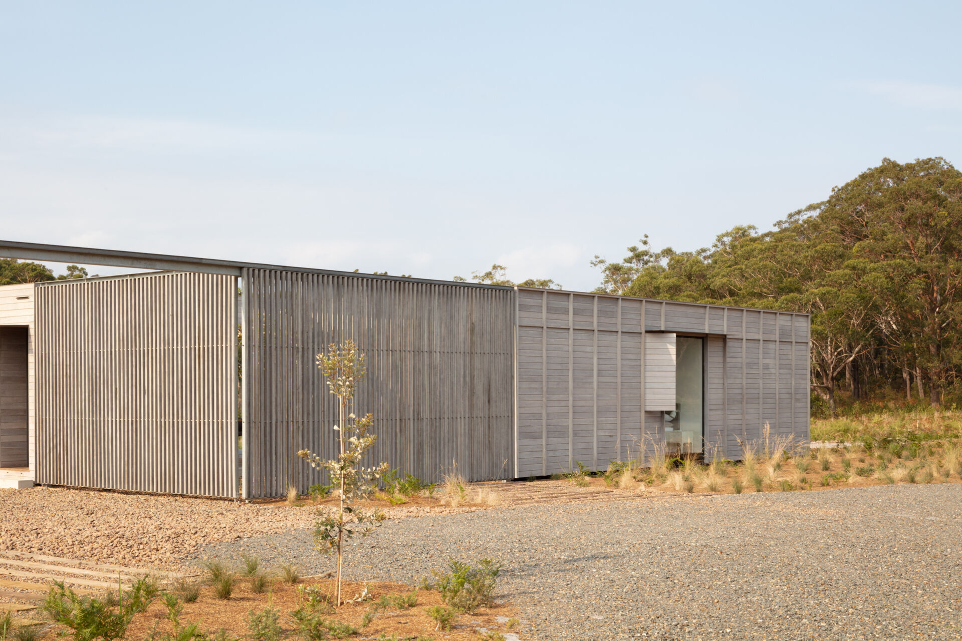 One of the house’s most distinctive features is the sliding screen positioned at the rear. When drawn, it encloses a private courtyard, creating a contained and contemplative outdoor room. When opened, it dissolves the boundary entirely, framing sweeping views and allowing the home to breathe with the environment. This duality adds a layer of flexibility rarely seen in homes of this scale.