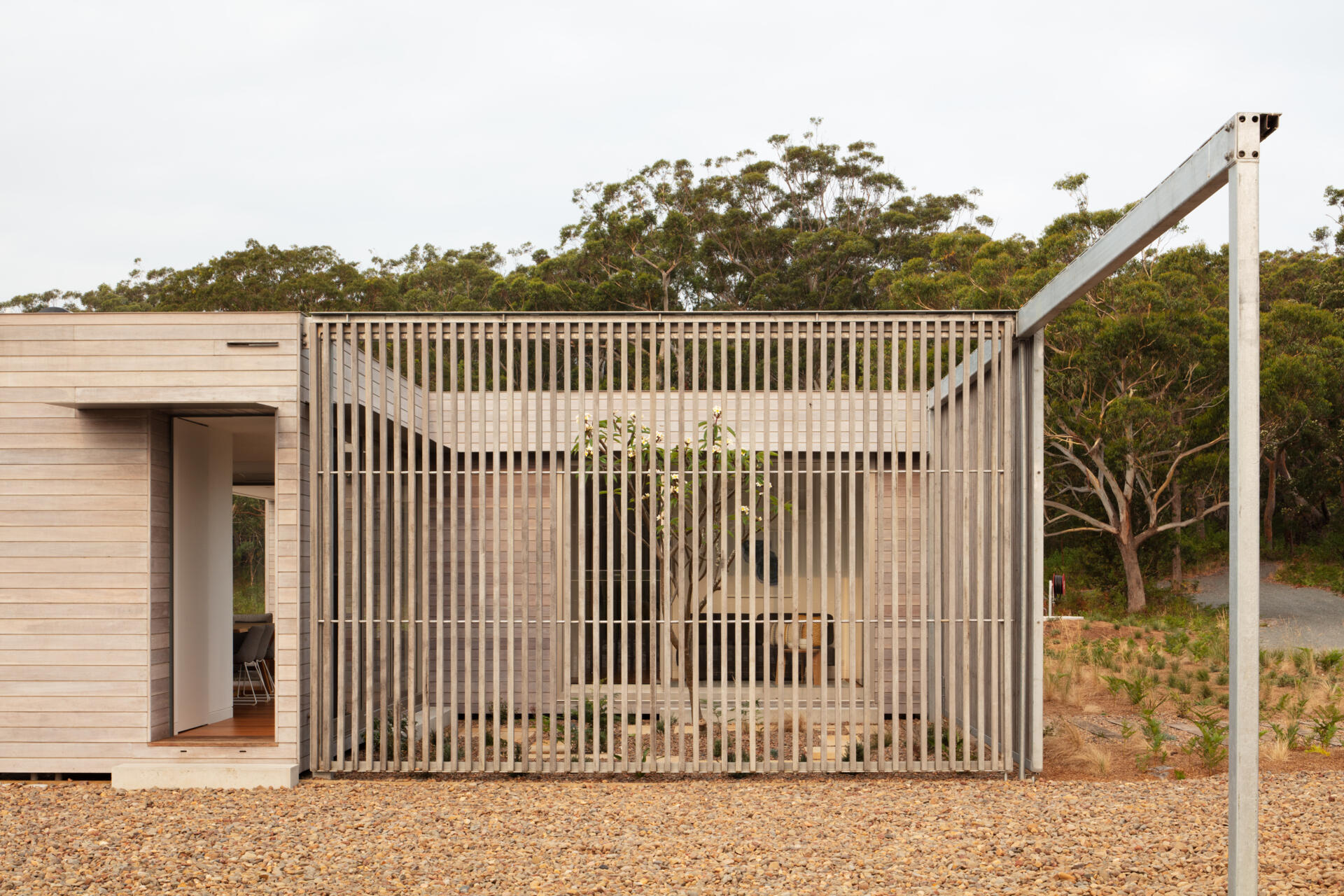 One of the house’s most distinctive features is the sliding screen positioned at the rear. When drawn, it encloses a private courtyard, creating a contained and contemplative outdoor room. When opened, it dissolves the boundary entirely, framing sweeping views and allowing the home to breathe with the environment. This duality adds a layer of flexibility rarely seen in homes of this scale.