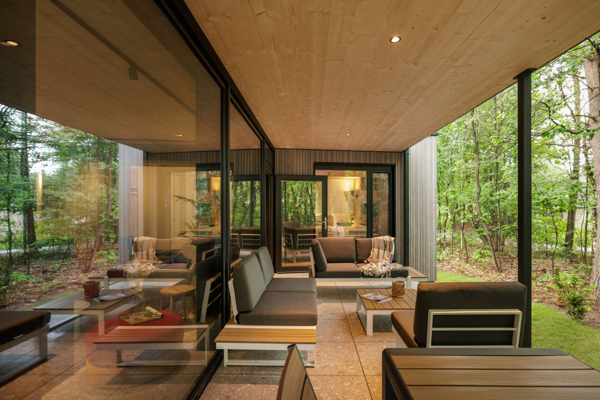 This modern prefab cottage features a private outdoor deck that extends into the woods, offering a peaceful spot to unwind and reconnect with nature.