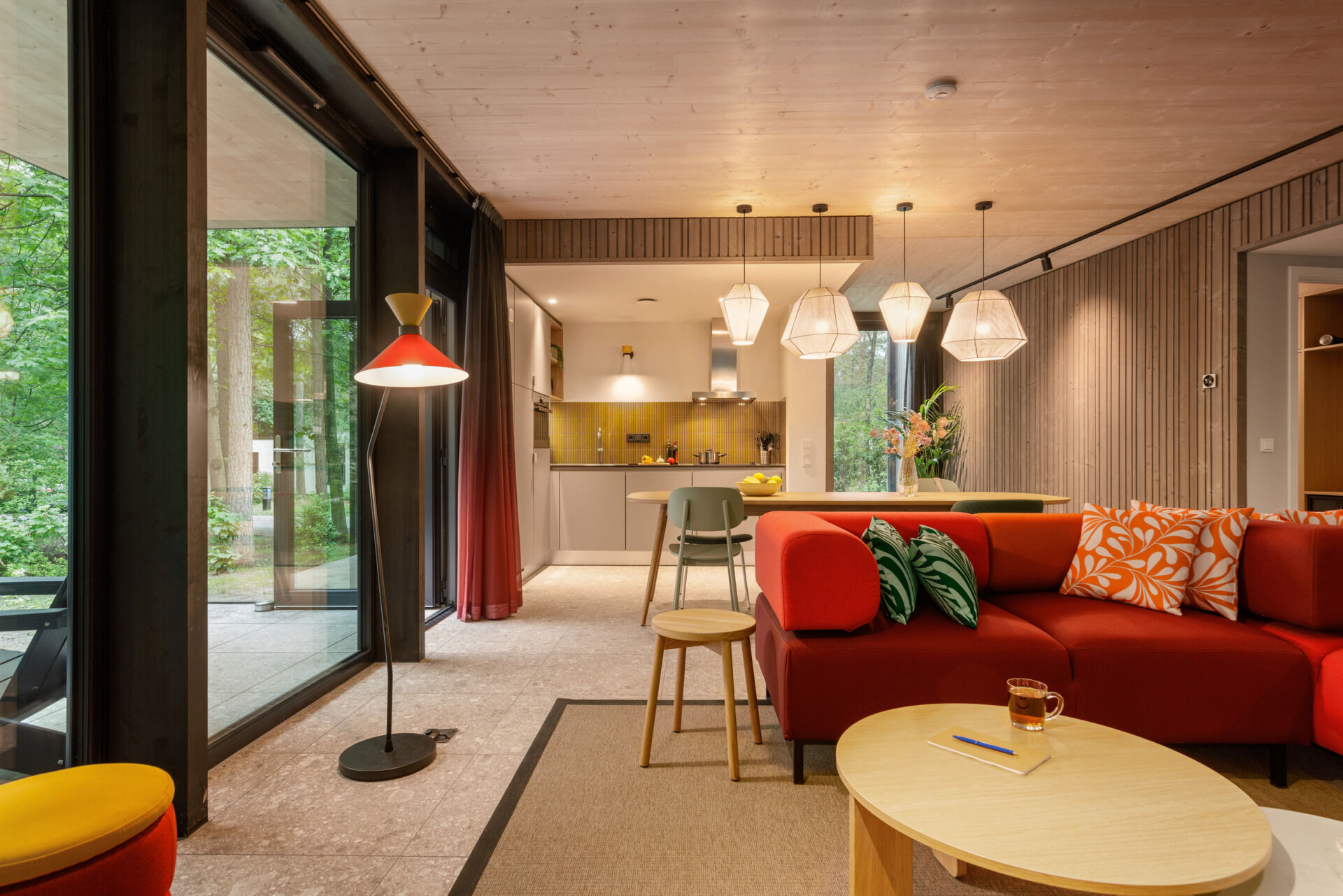 Inside this modern prefab cottage, a flexible corner sofa and oversized dining table anchor an open-plan space designed for comfort and togetherness.