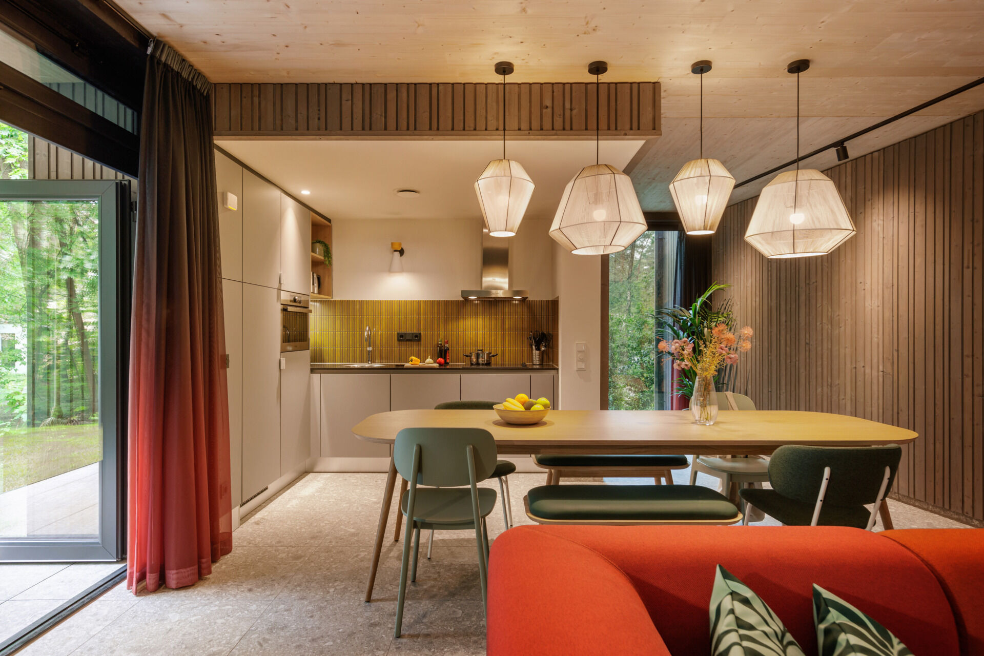 Inside this modern prefab cottage, a flexible corner sofa and oversized dining table anchor an open-plan space designed for comfort and togetherness.