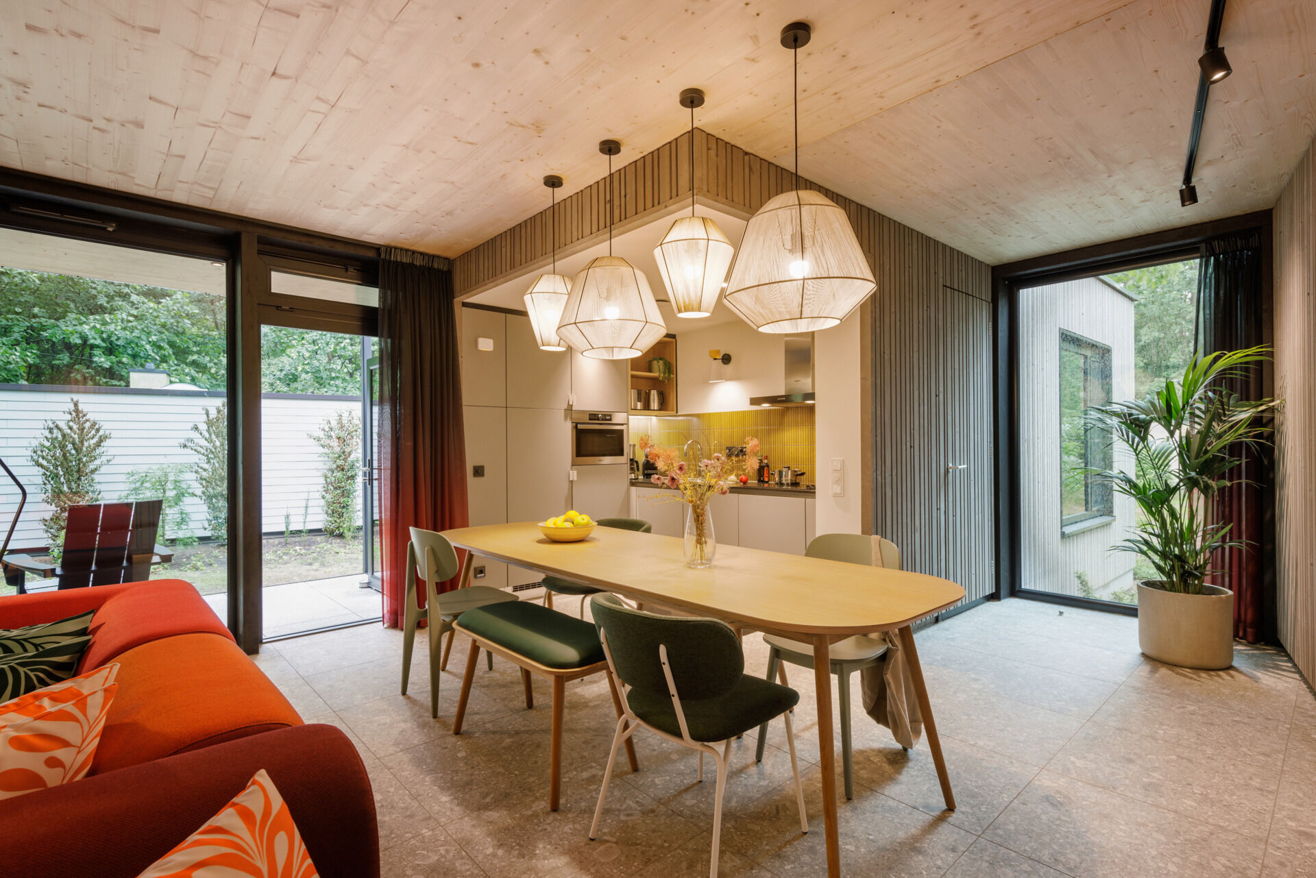 Inside this modern prefab cottage, a flexible corner sofa and oversized dining table anchor an open-plan space designed for comfort and togetherness.