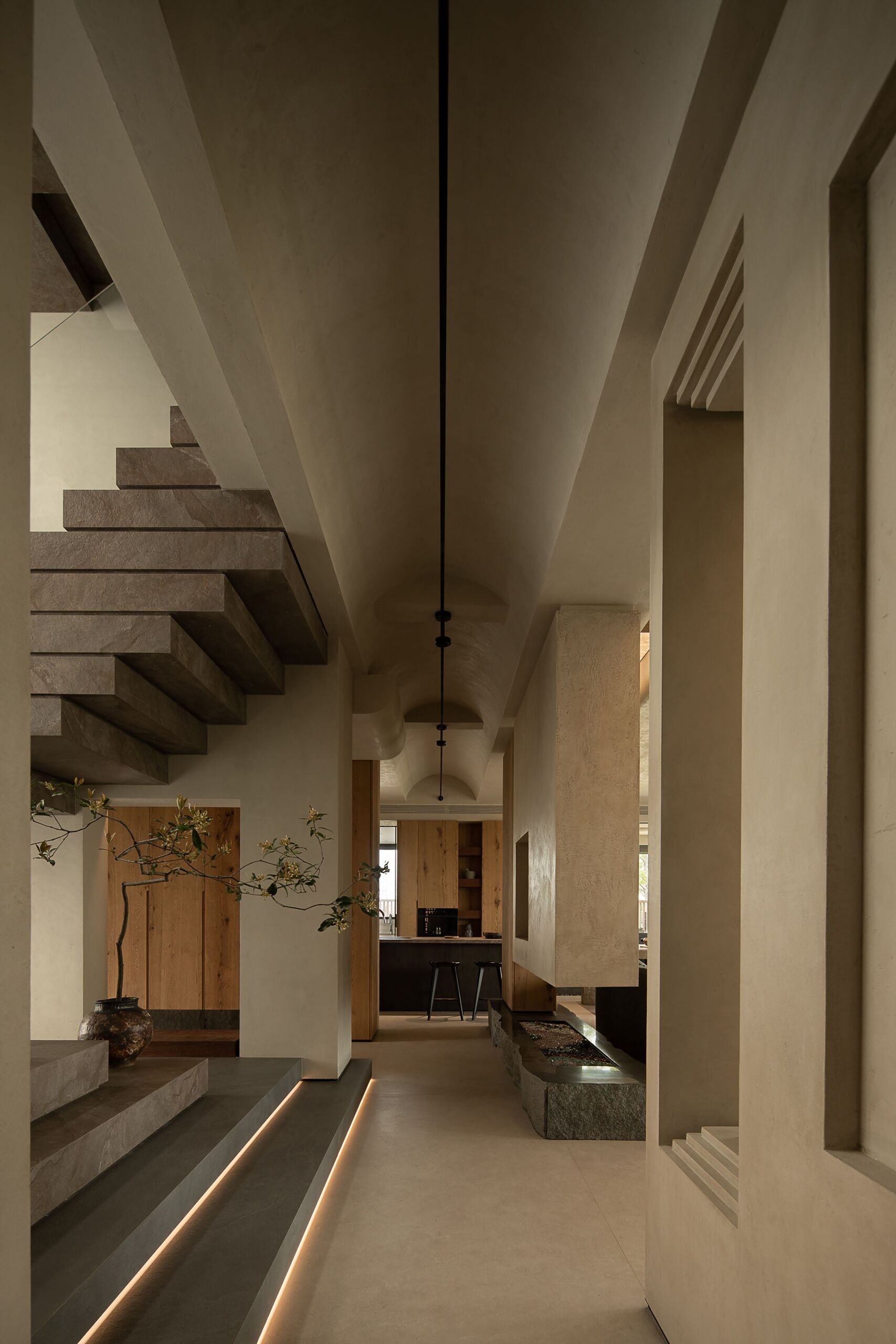 This sculptural staircase makes a bold architectural statement with its hefty stone treads and clean, floating form. Each step seems to hover in space, softened by the warm glow of daylight filtering through tall, frosted windows. A slim glass railing keeps the view uninterrupted, allowing the natural texture and subtle veining of the stone to shine.