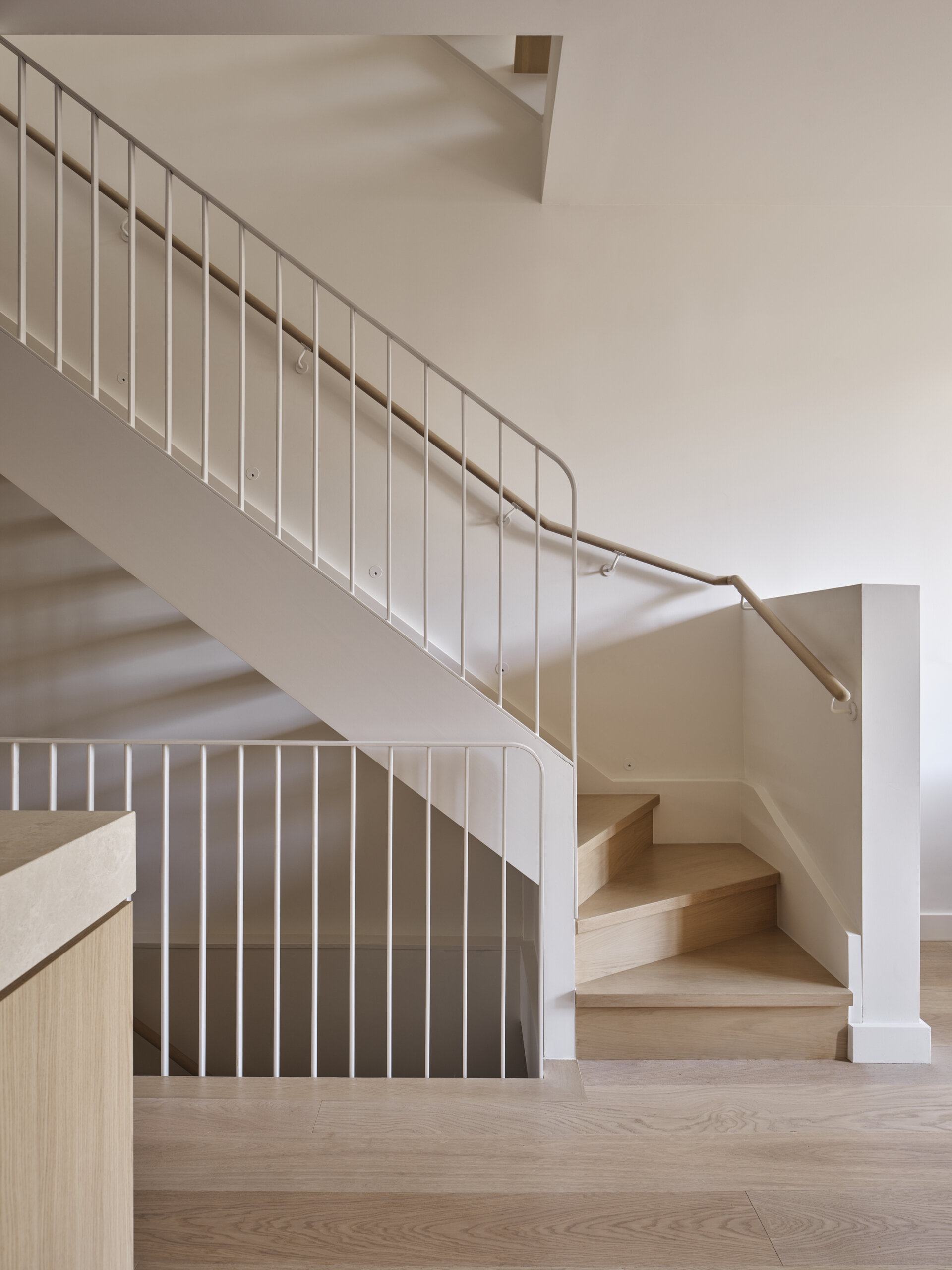 A sculptural staircase with a skylight above creates a vertical light shaft and maximizes space in this elegant three-level home.