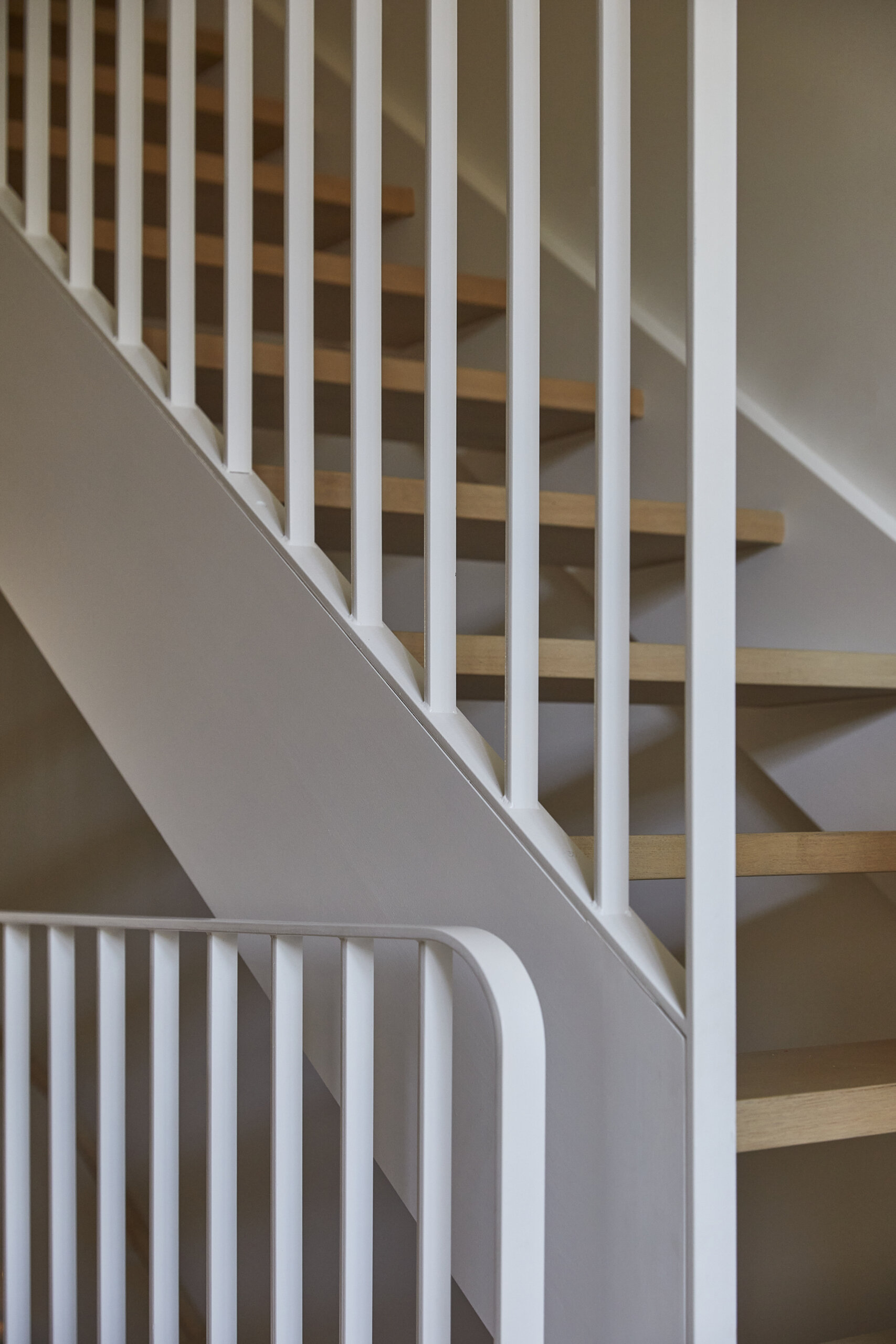 A sculptural staircase with a skylight above creates a vertical light shaft and maximizes space in this elegant three-level home.