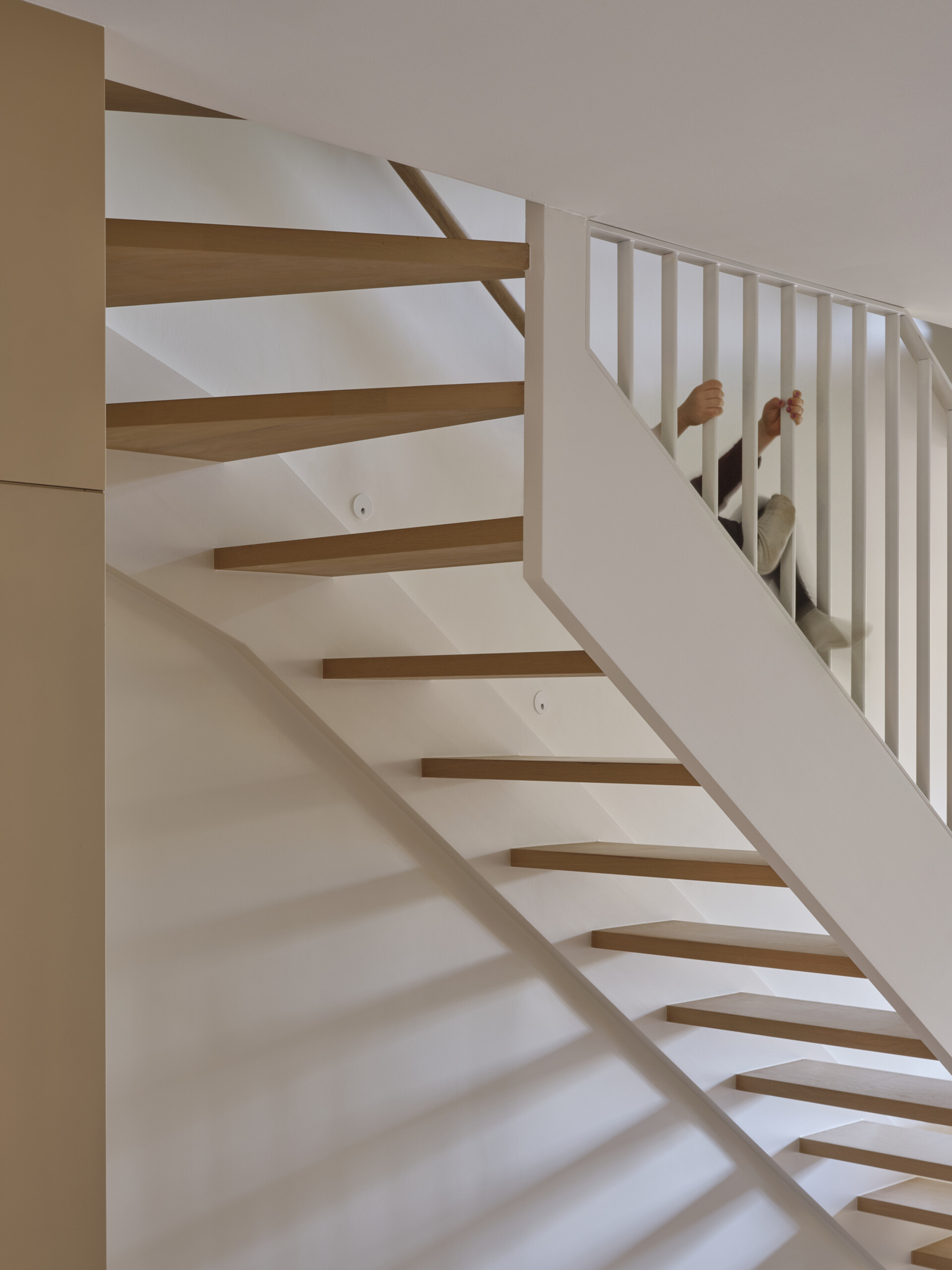A sculptural staircase with a skylight above creates a vertical light shaft and maximizes space in this elegant three-level home.
