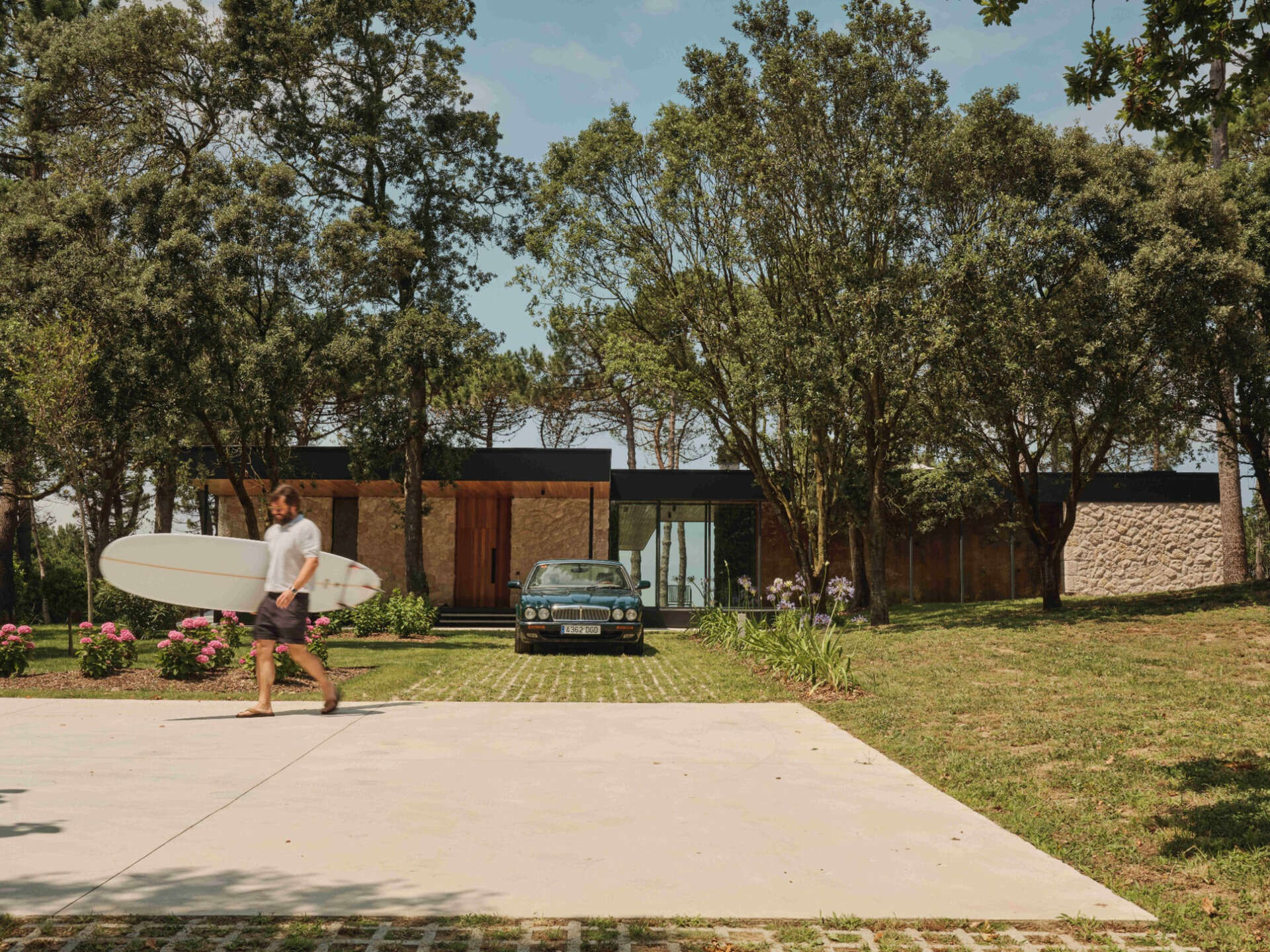 This modern home has limestone walls and large glass panels that form a rhythm of solid and void, while wood adds a sense of warmth.